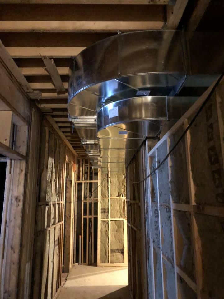 Un long couloir avec de nombreux tuyaux métalliques suspendus au plafond.