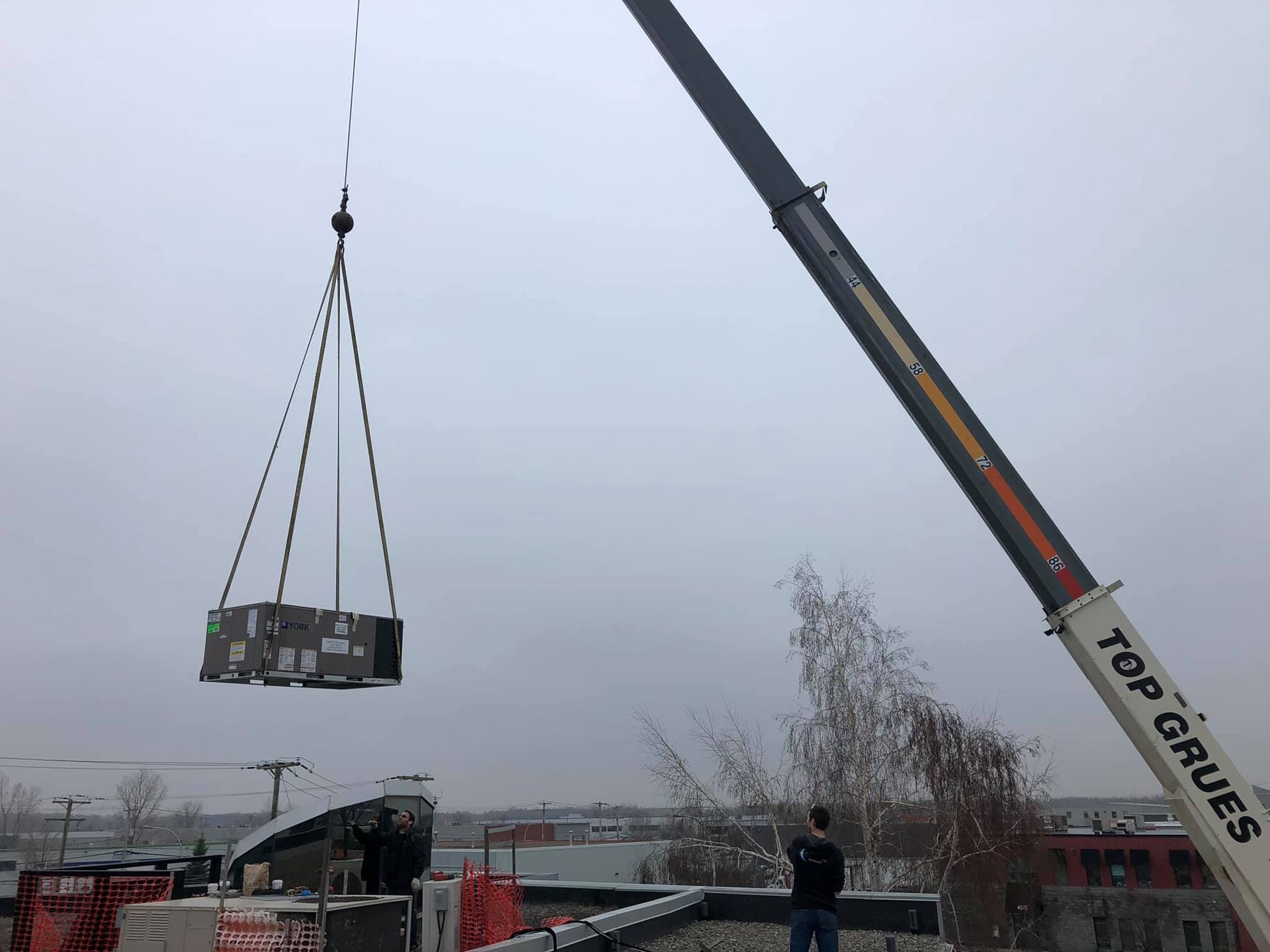 Un homme se tient à côté d'une grue qui dit des chaises hautes