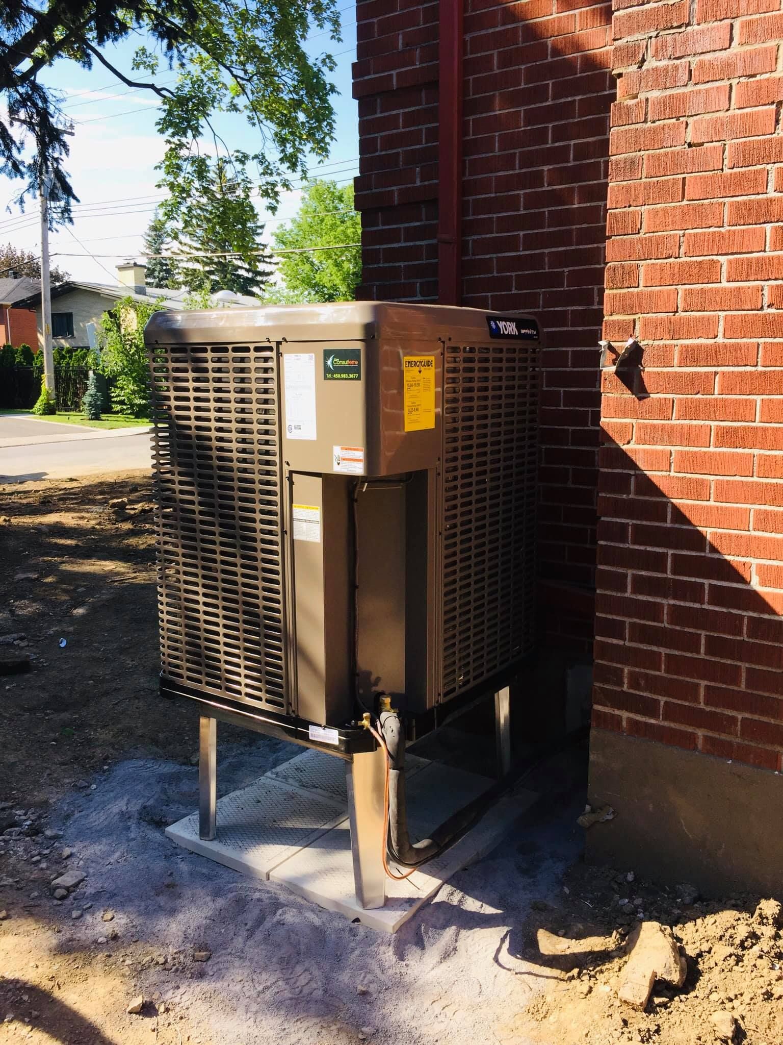 Un climatiseur est posé sur le côté d'un bâtiment en brique.
