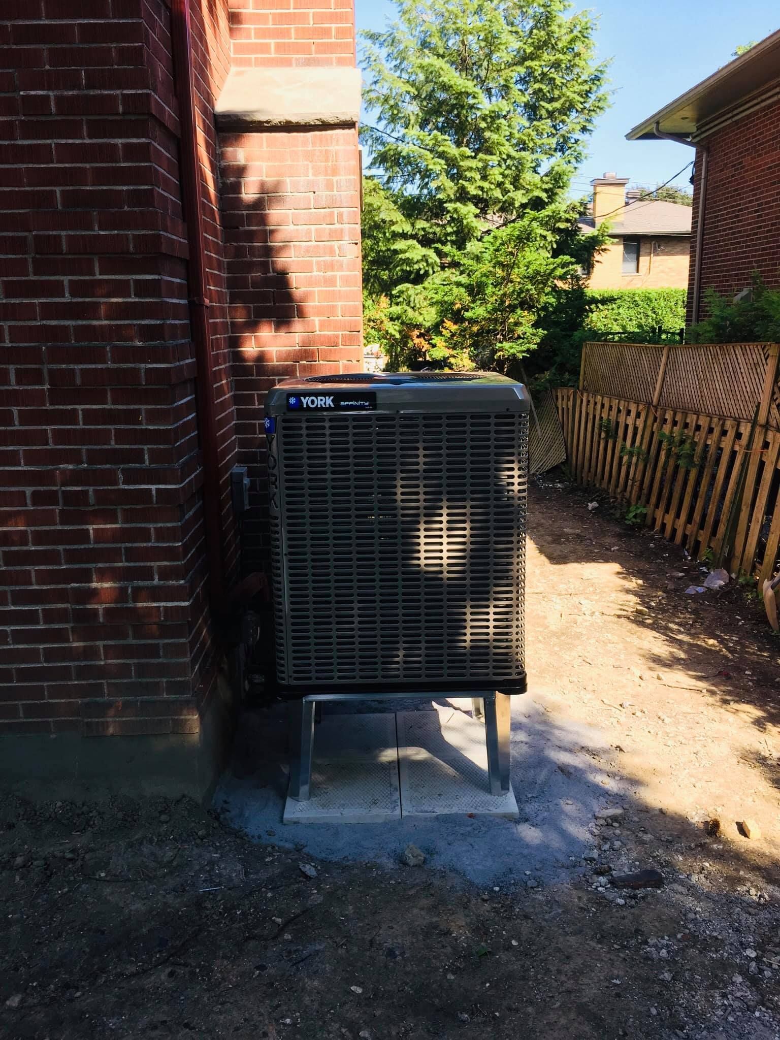 Un climatiseur est posé sur le côté d'un bâtiment en brique.