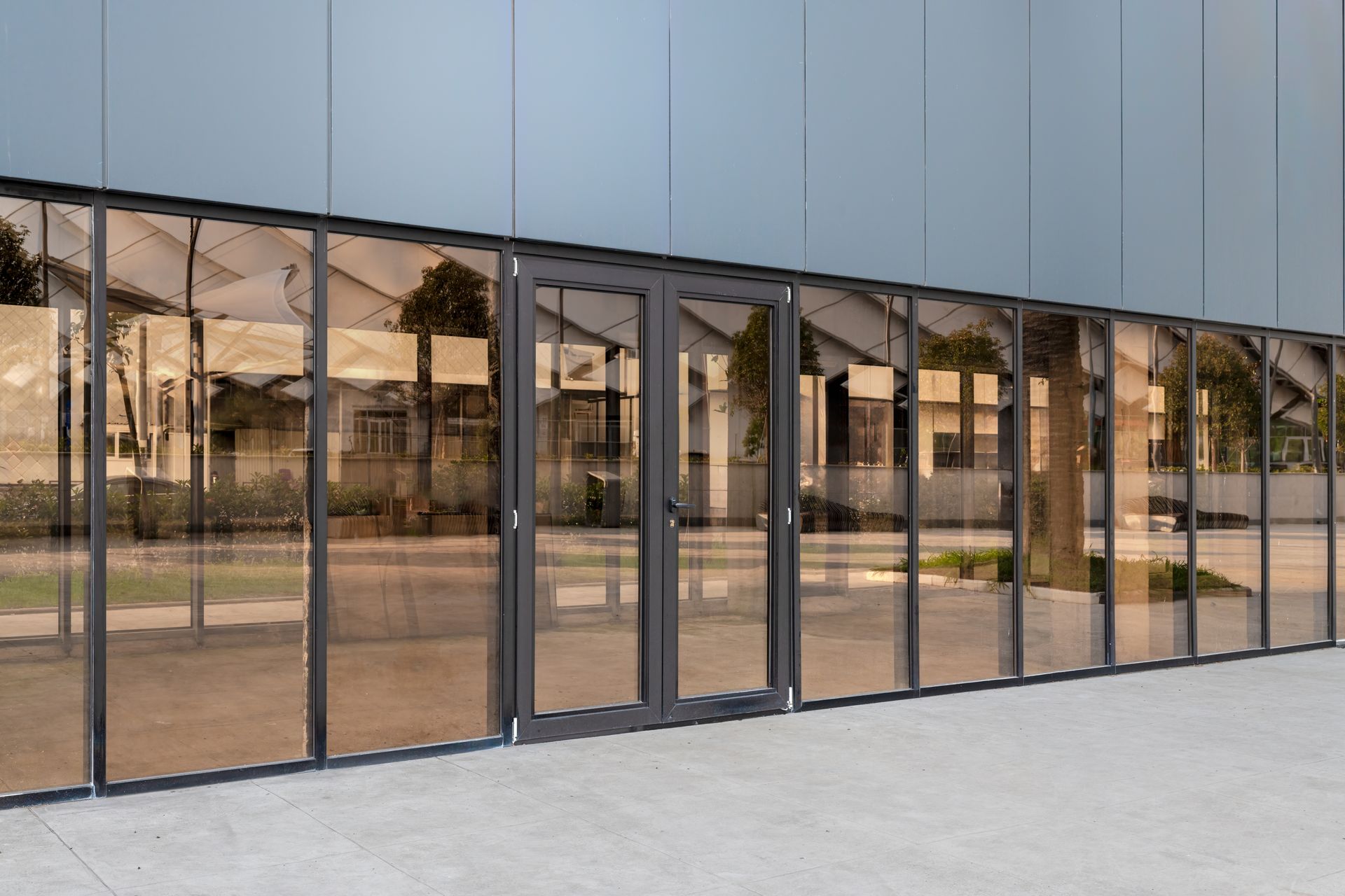Glass doors and panels with reflective tint on a modern building exterior.