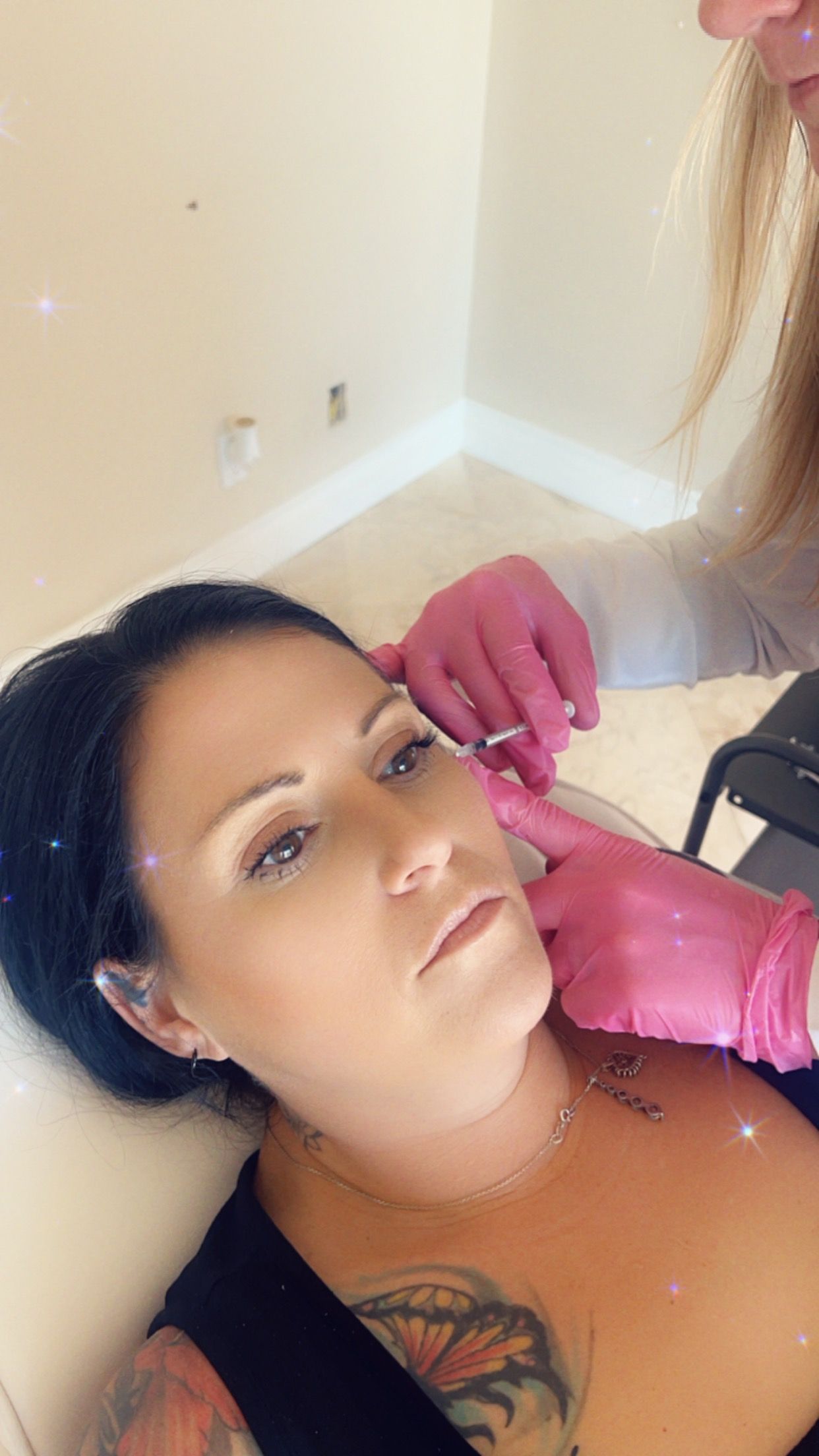 Jordan's pink gloved hands injecting a womans face with botox