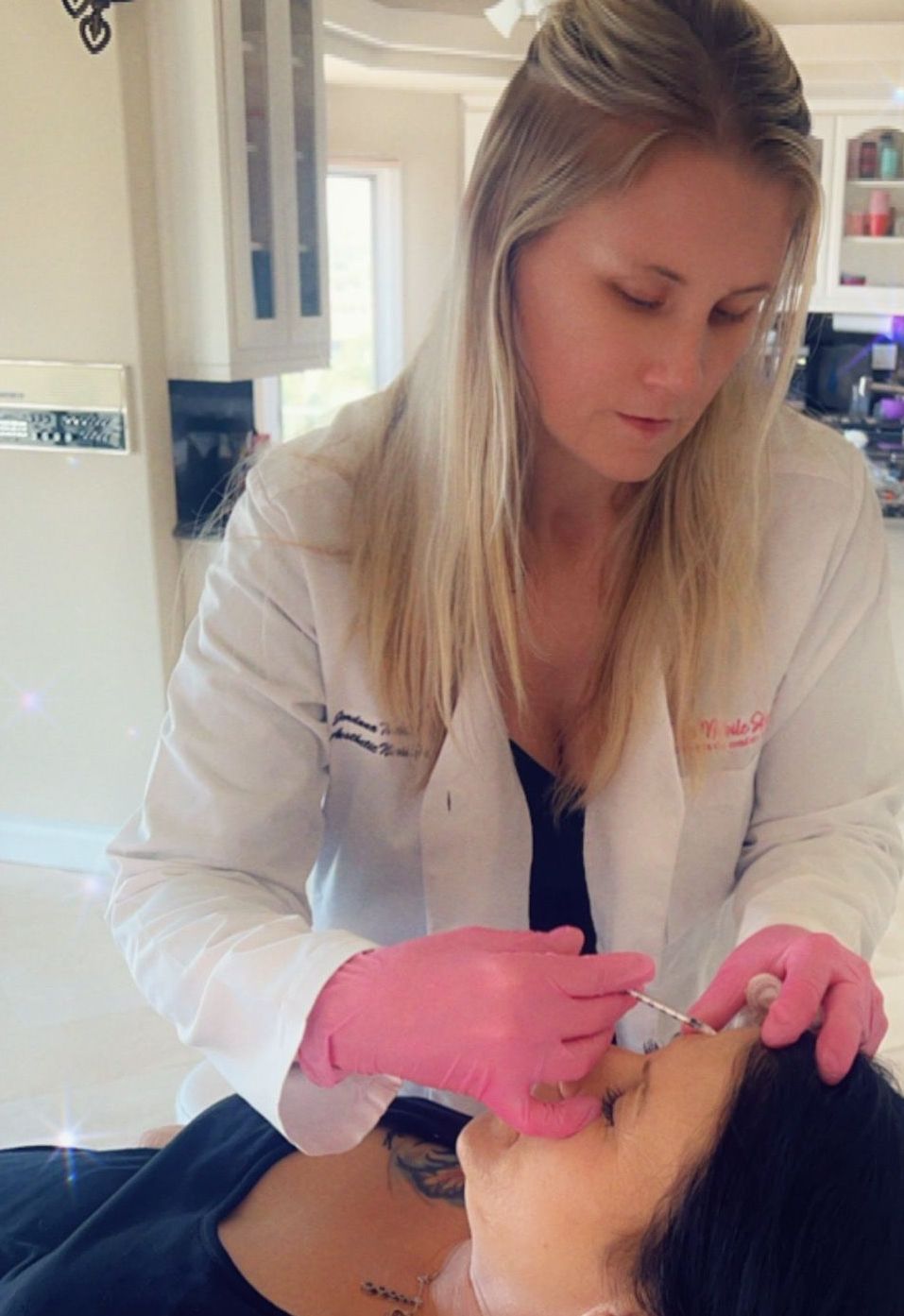 Jordan injecting womans face with botox. She's laying on injector chair