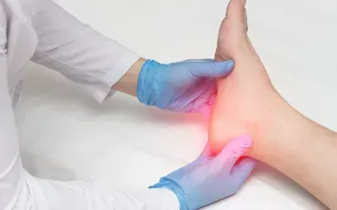 A doctor is examining a patient 's foot with blue gloves.