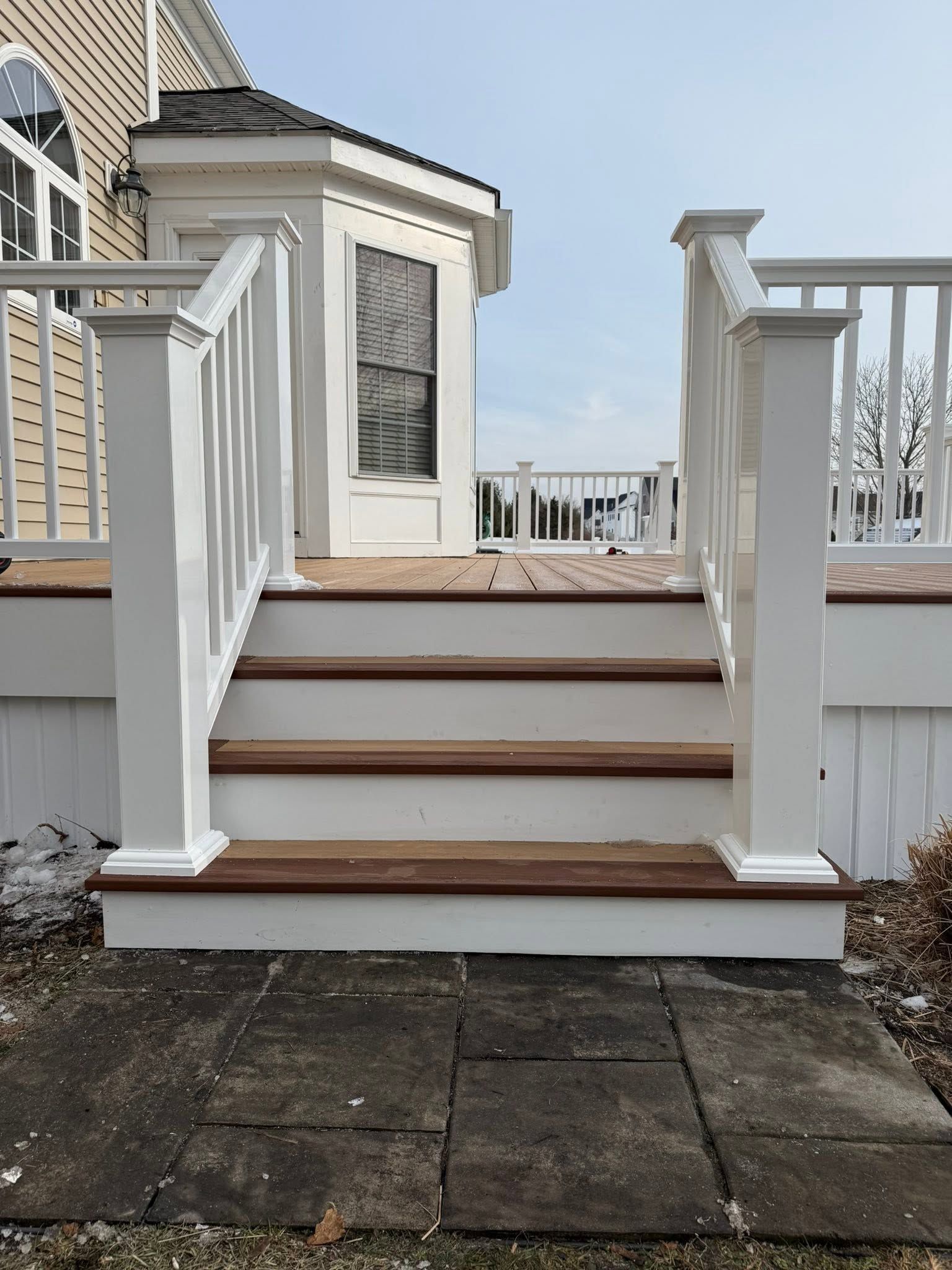 Front steps with white railings leading to a small porch and door on a house