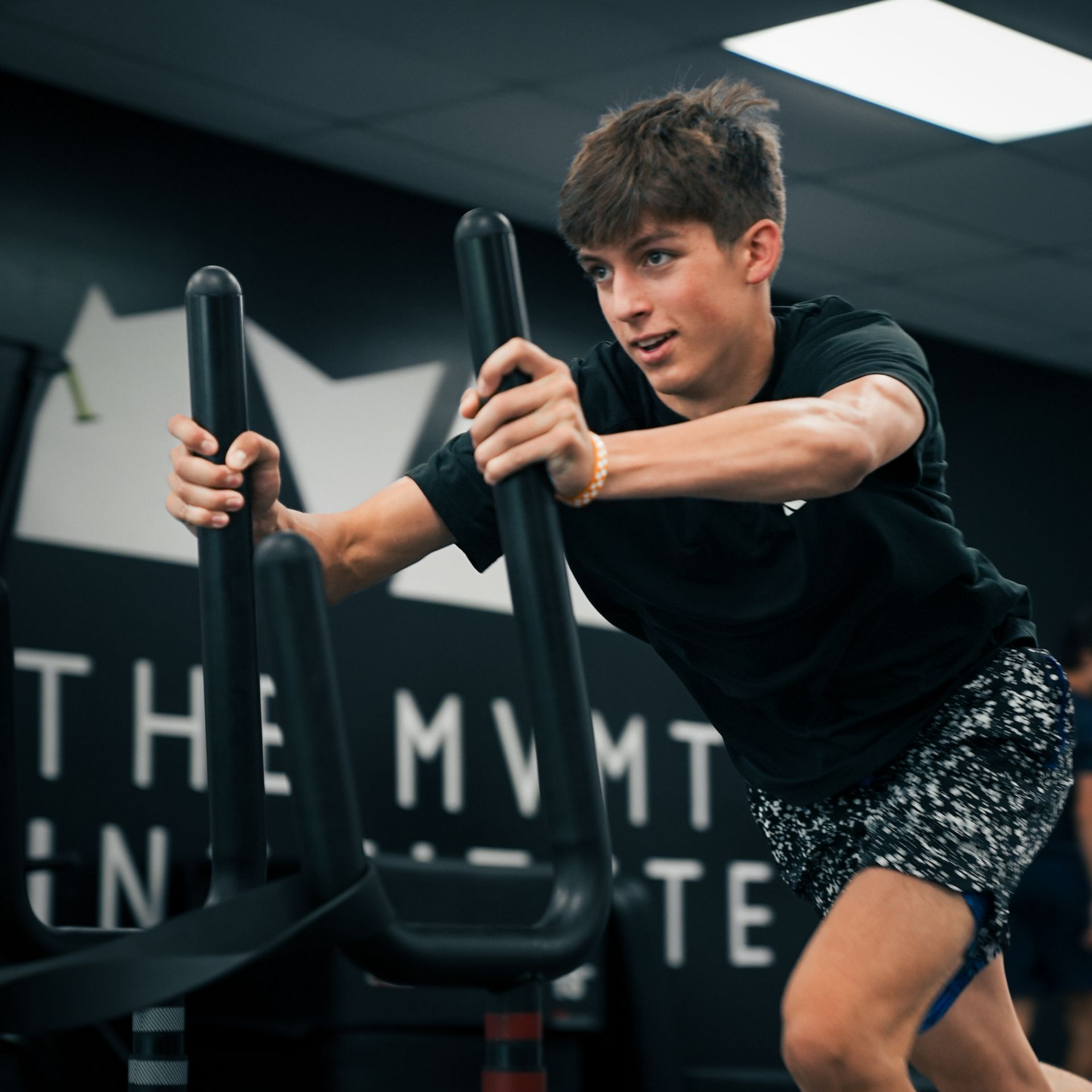 A boy running while pushing a weighted sled as part of a workout routine.