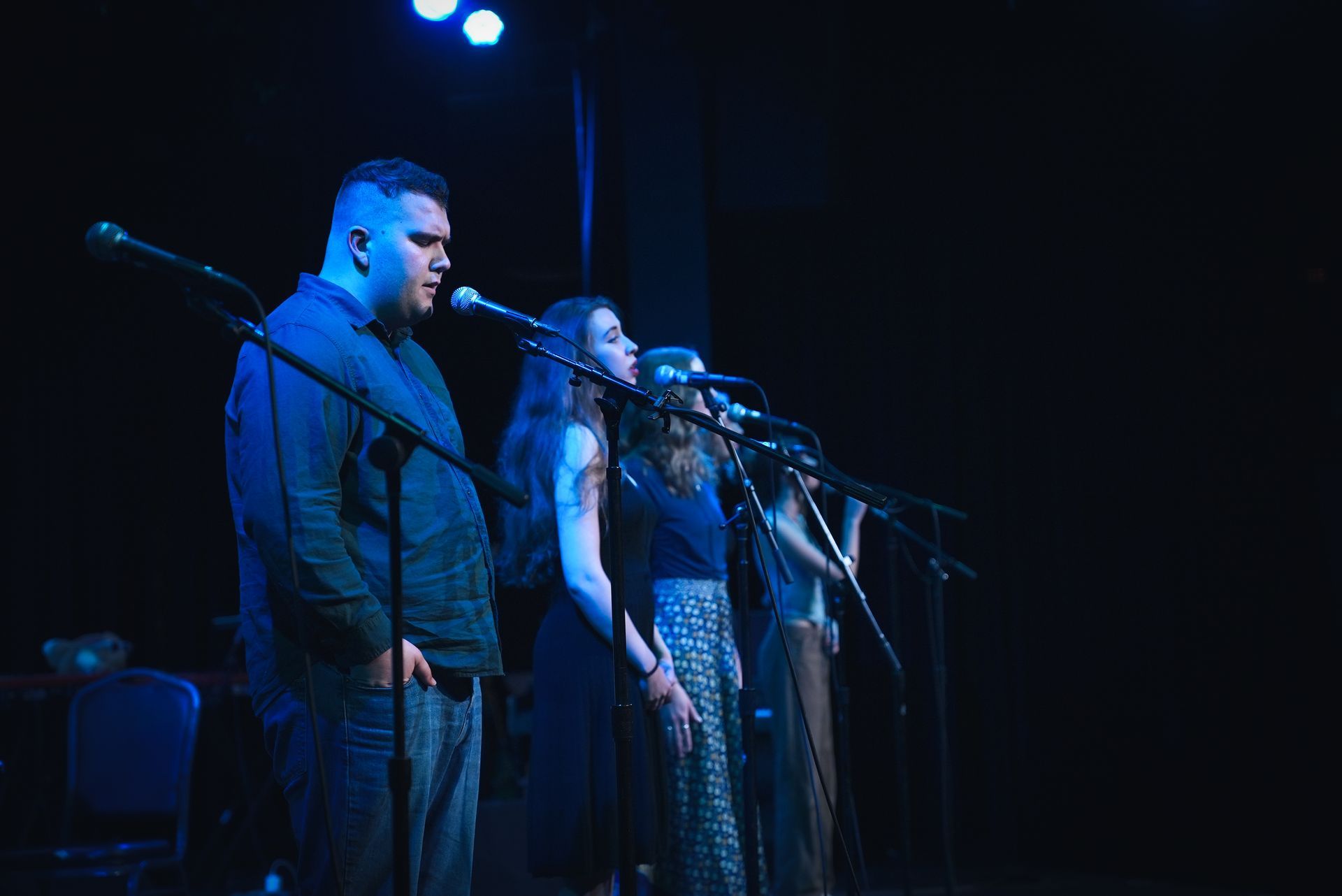 A row of singers perform and feel the emotions of the music at a live concert.
