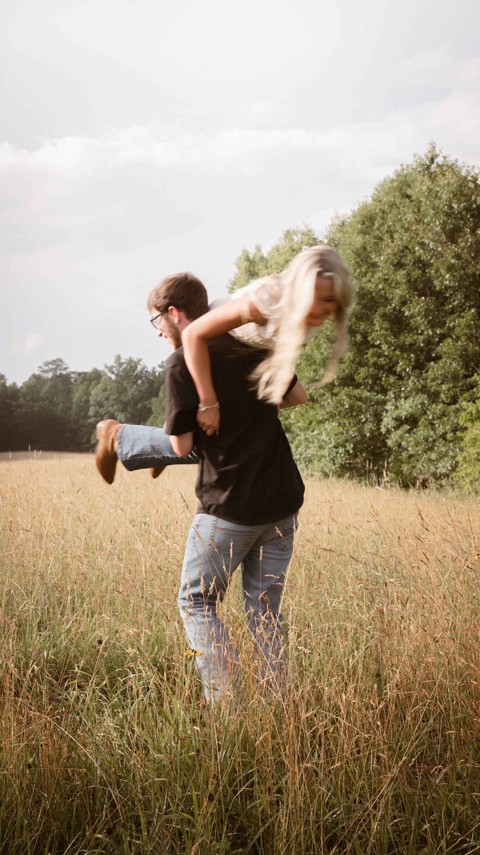 Wide shot of a man picking his girlfriend up and spinning with her.