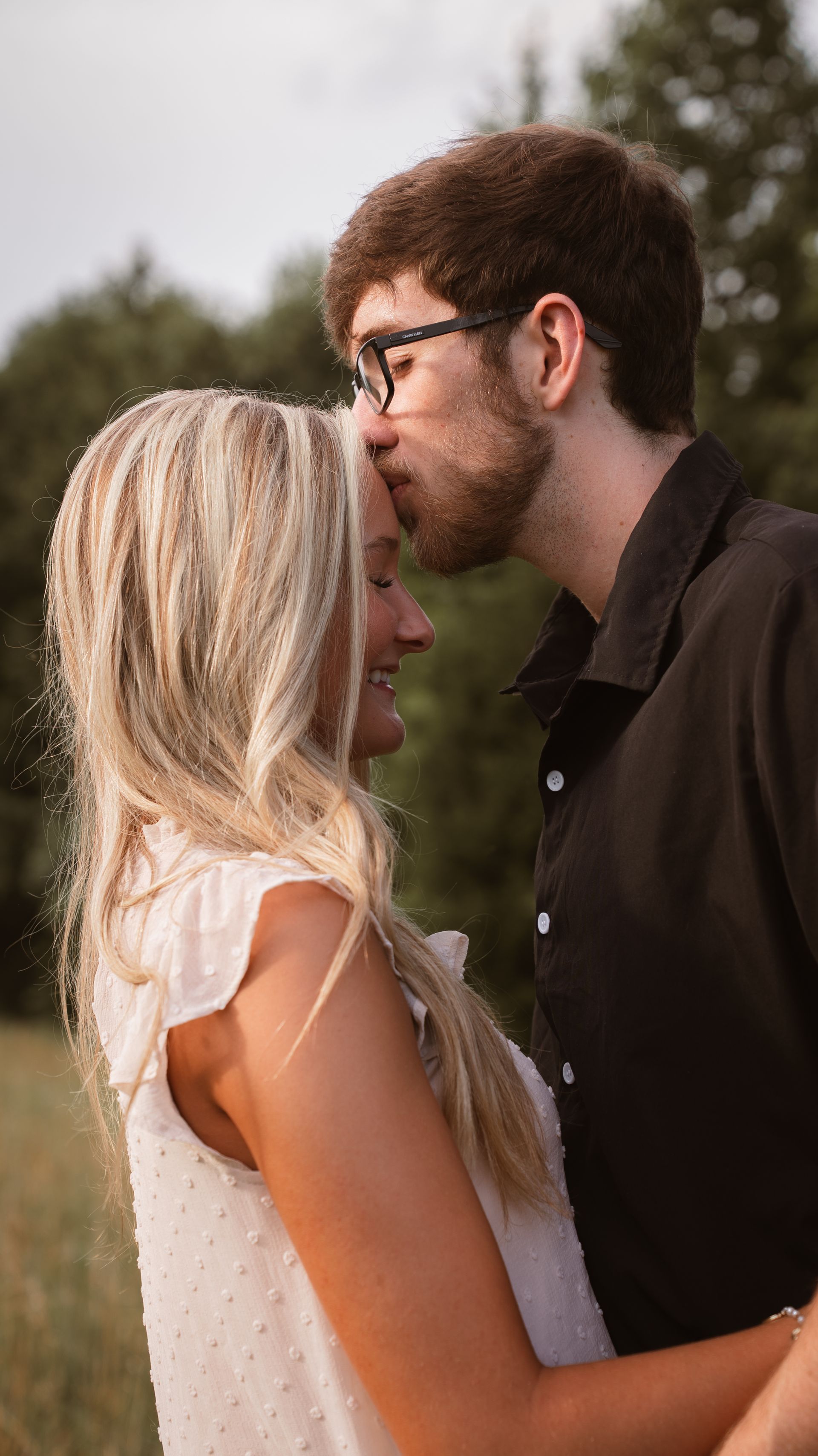 A man kisses his girlfriend on the forehead for a couple photo shoot.