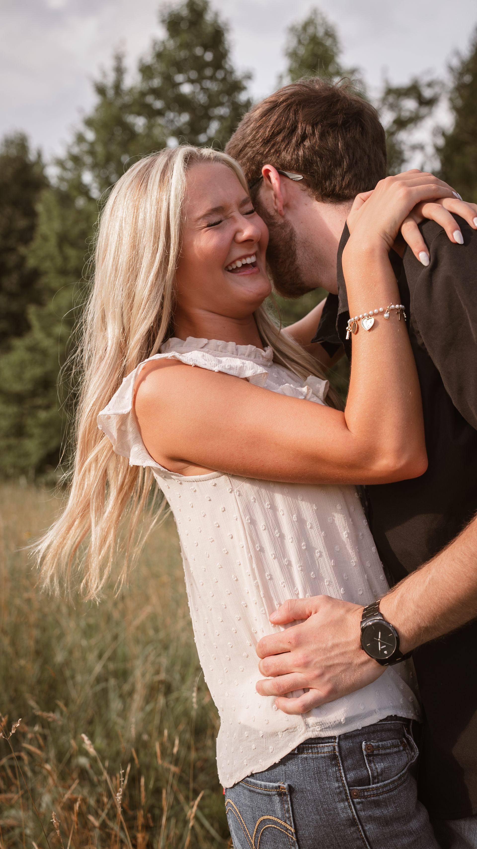 A man whispers into his girlfriend's ear as she laughs at what he's saying.