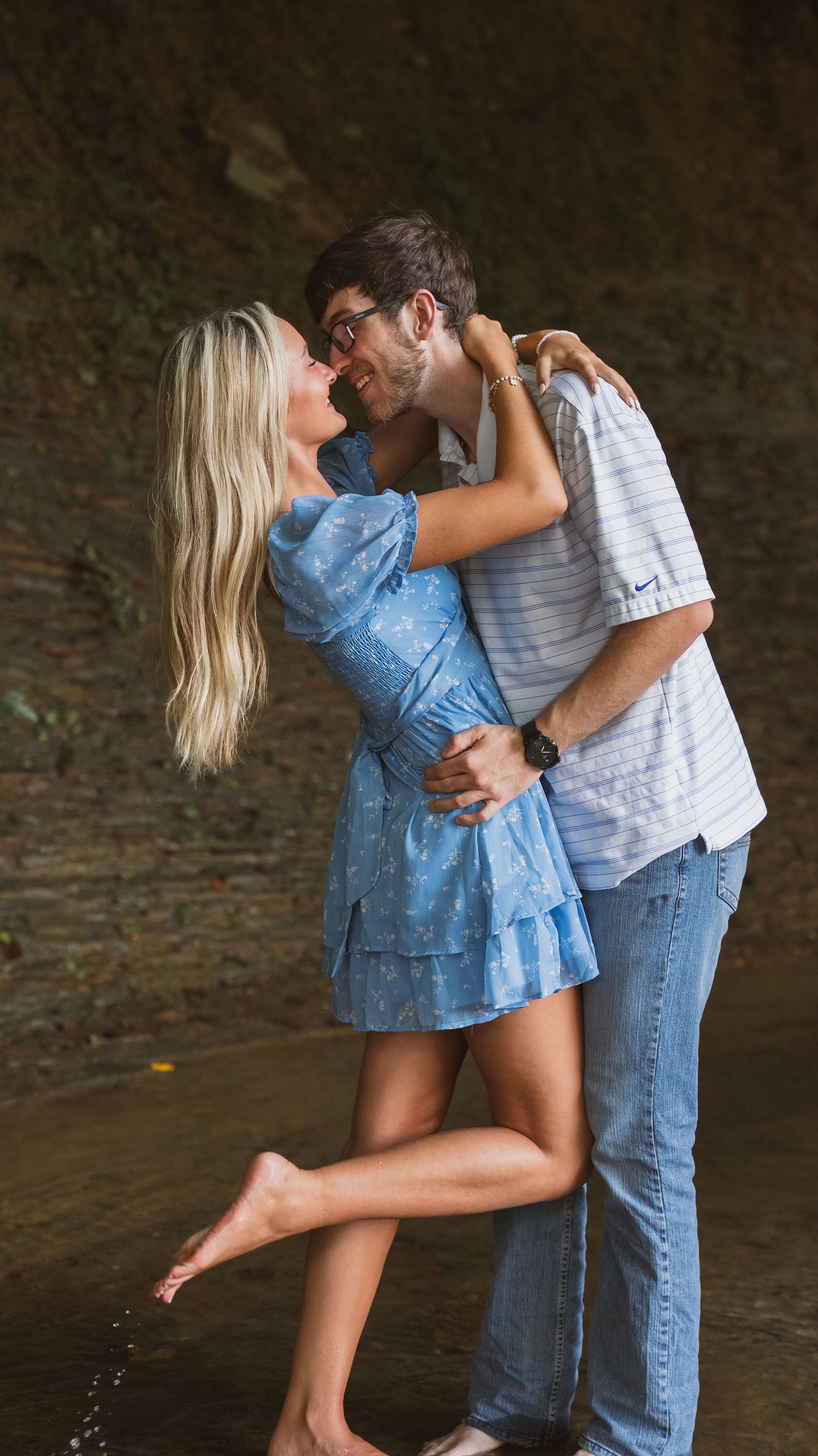 A man holds his girlfriend by the waist and smiles at her for a couple photo shoot.