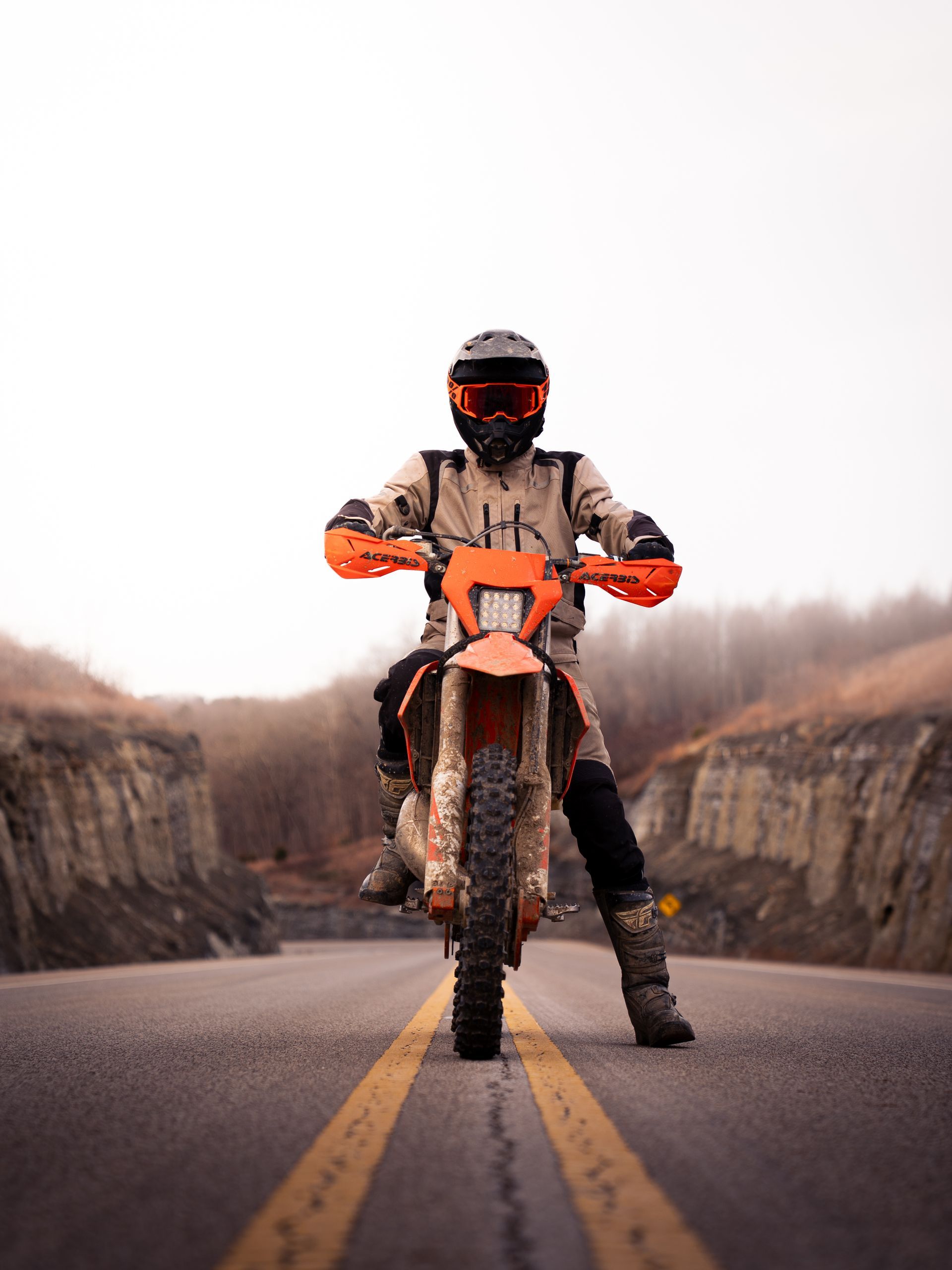 Boy sitting on a dirk bike in the middle of a mountain road looking at the camera for senior photos.