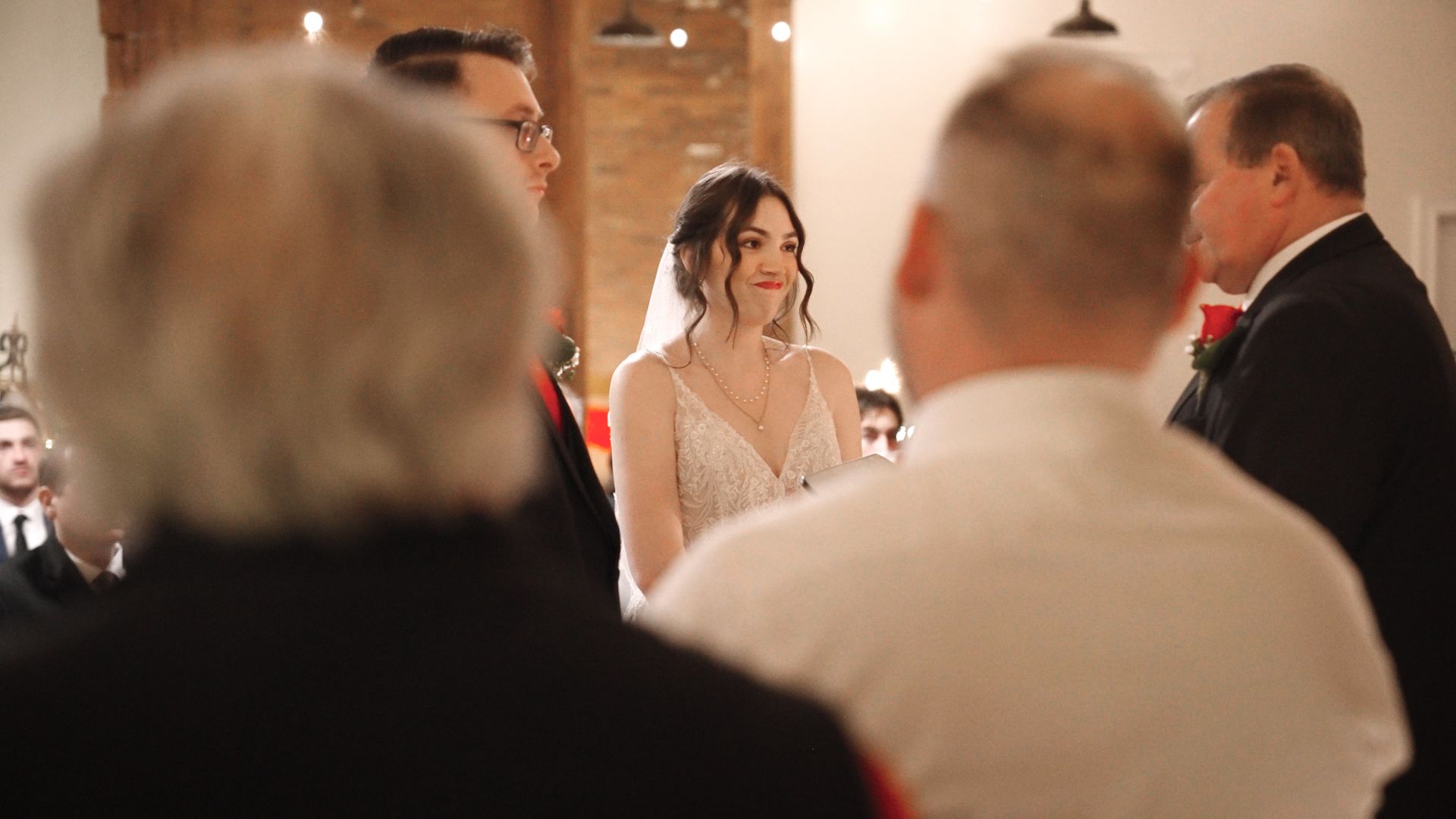 A smiling bride stands at the alter next to her groom.