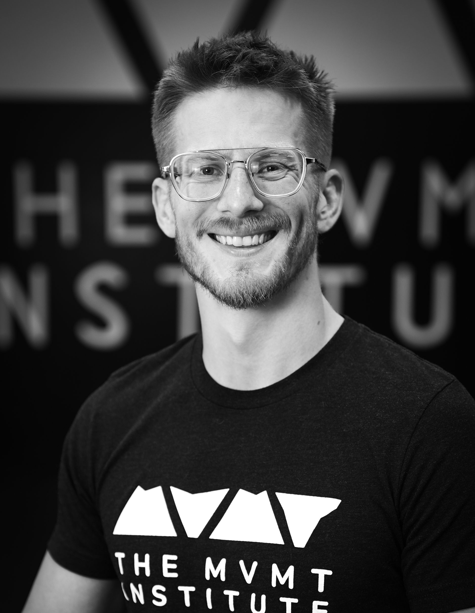 A man wearing glasses poses for a professional headshot.