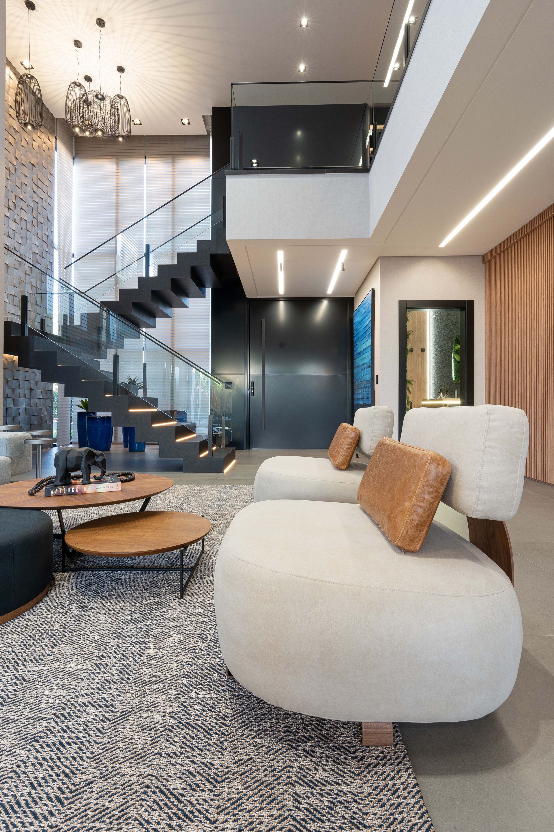 Sala de estar moderna com escada, design de dois andares. Sofás brancos, almofadas marrons, tapete, mesa de centro, parede escura.