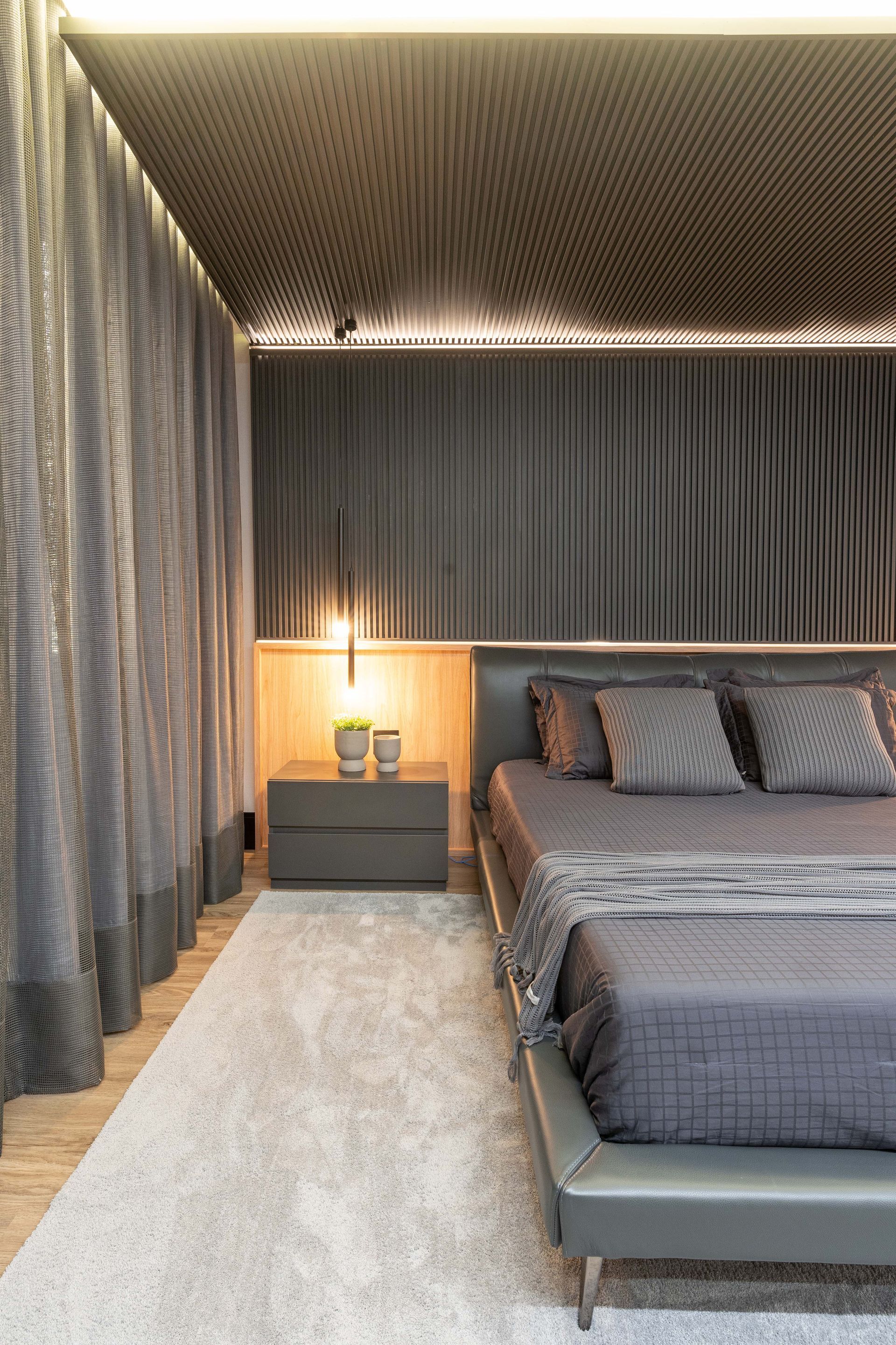 Quarto cinza moderno com cama, mesa de cabeceira e cortinas.