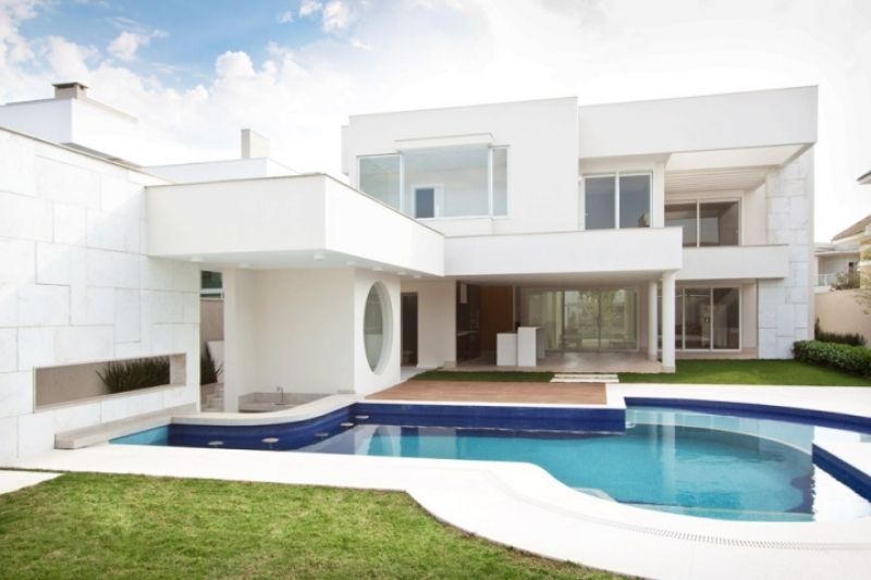 Casa branca moderna com piscina e gramado verde.