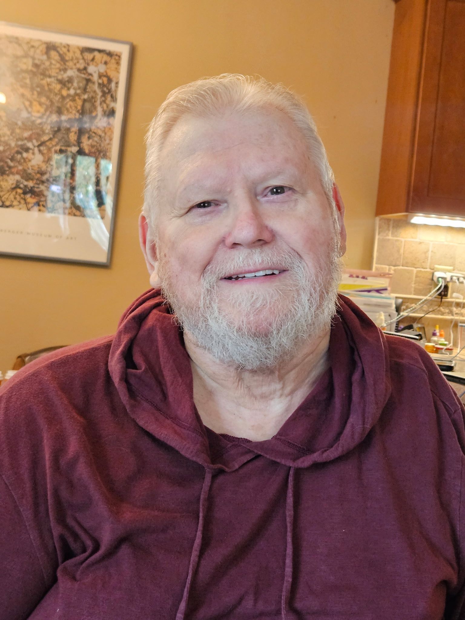 Smiling person in a maroon hoodie indoors.