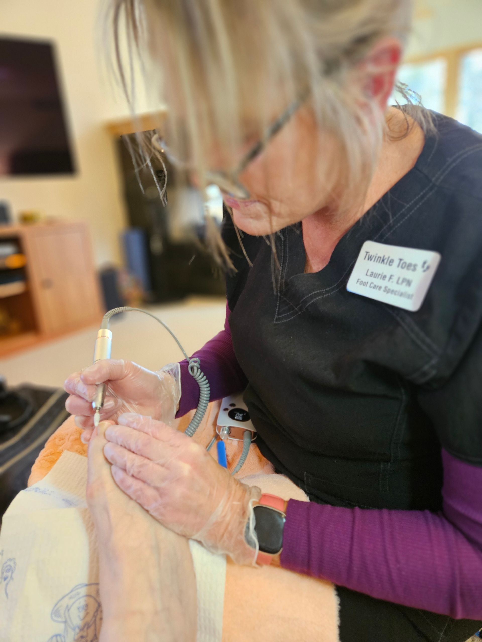 A medical professional wearing gloves performs a nail procedure on a patient's foot.