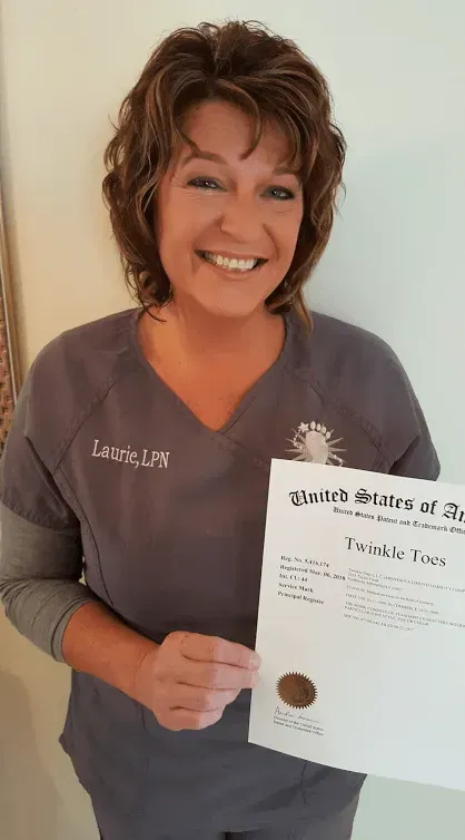 Woman in gray scrubs holding a document, smiling.