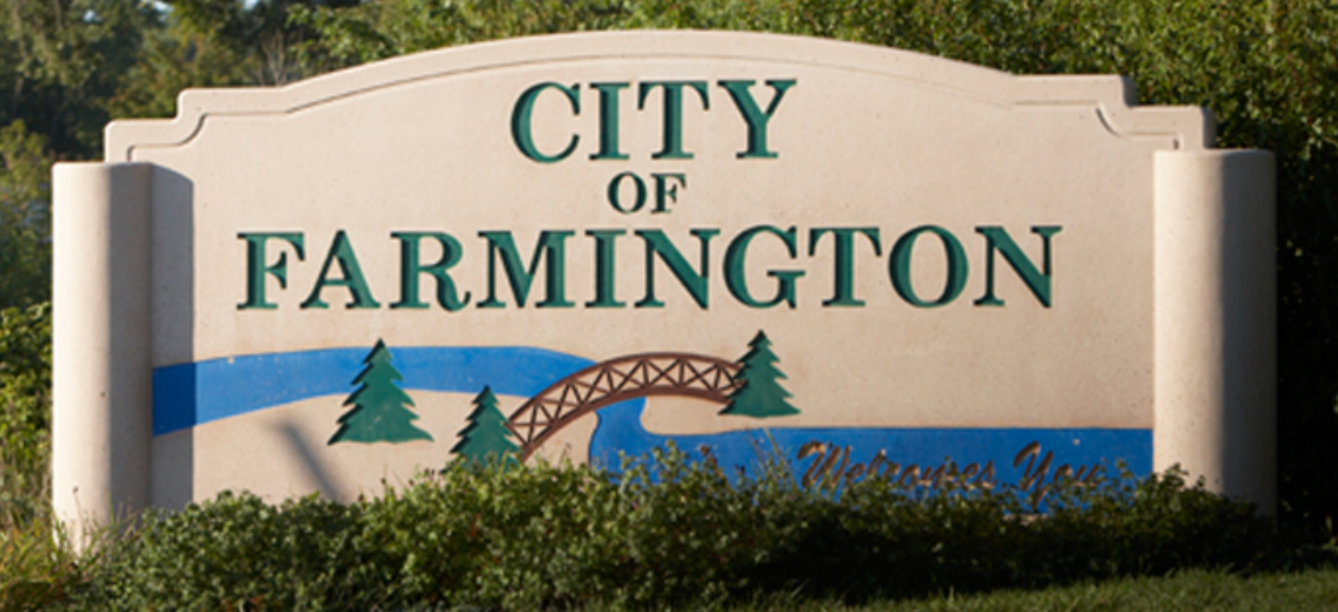 City of Farmington sign in green lettering with blue stripe and bridge graphic