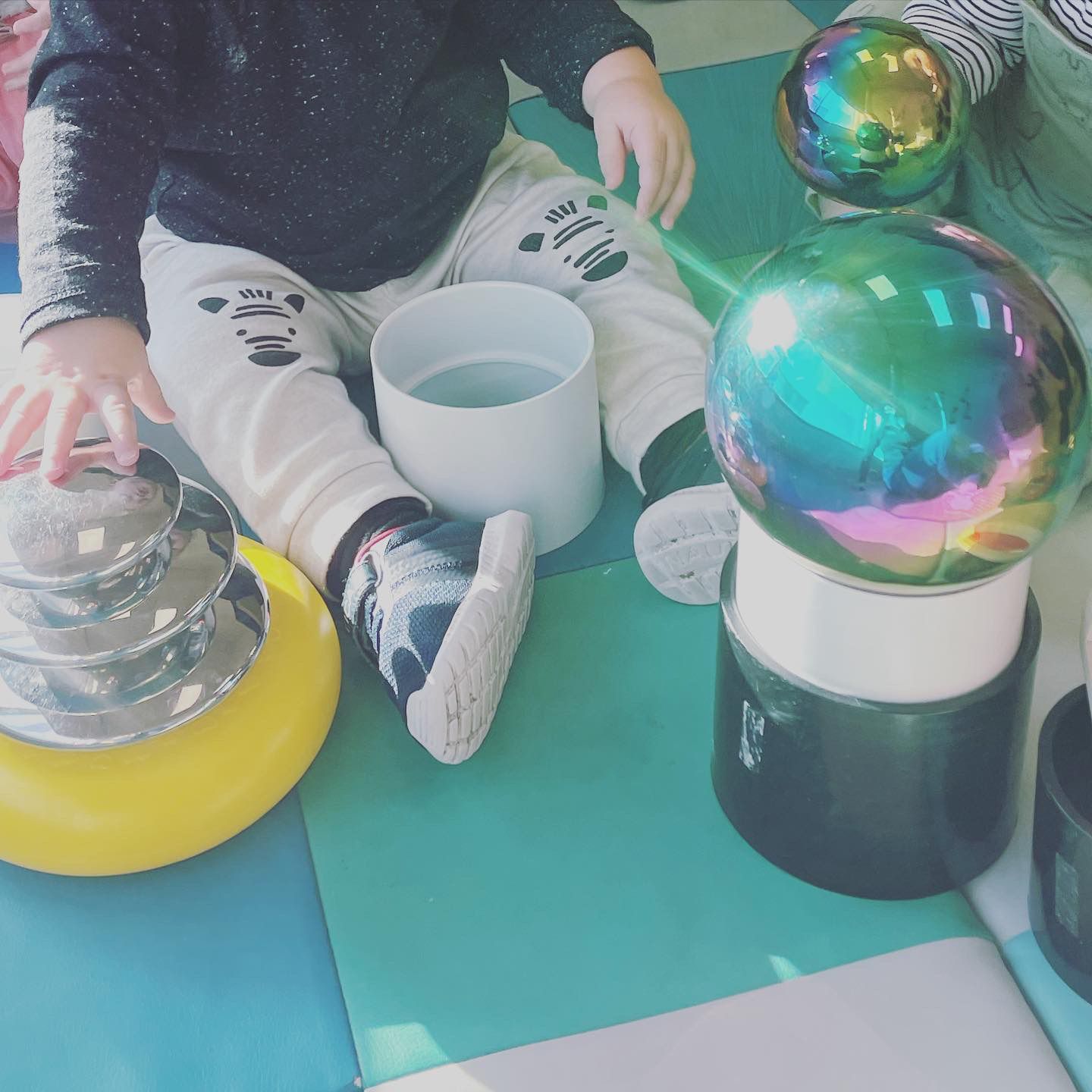 Child sitting on mats with colorful sensory balls and play toys indoors