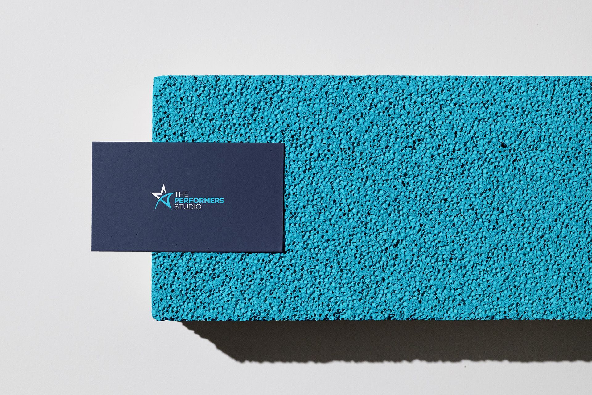 Business card on blue textured surface, featuring a star logo.