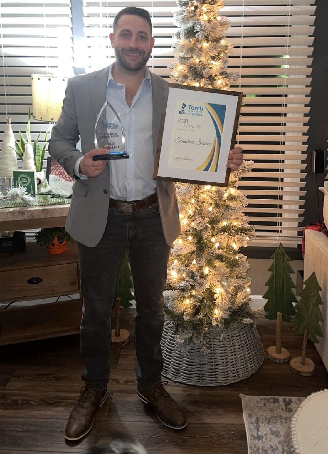 man standing holding a trophy and certificate