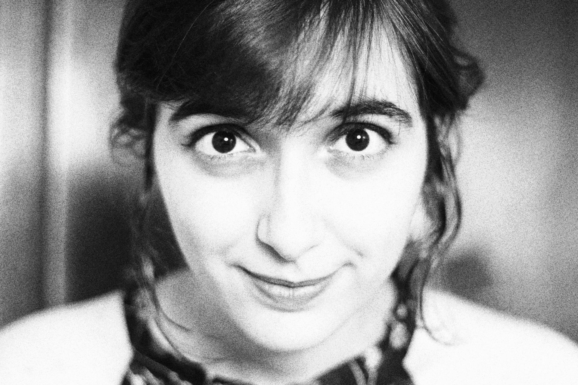 Black-and-white close-up portrait of a smiling person with dark hair and bangs