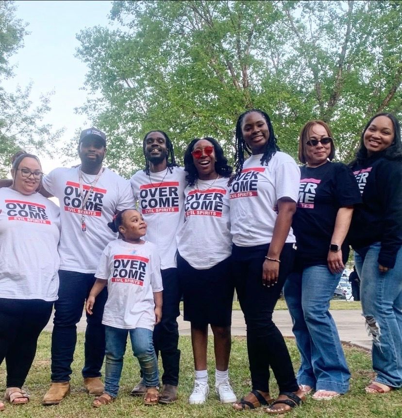 Group wearing matching “Overcome” shirts posing outdoors under trees