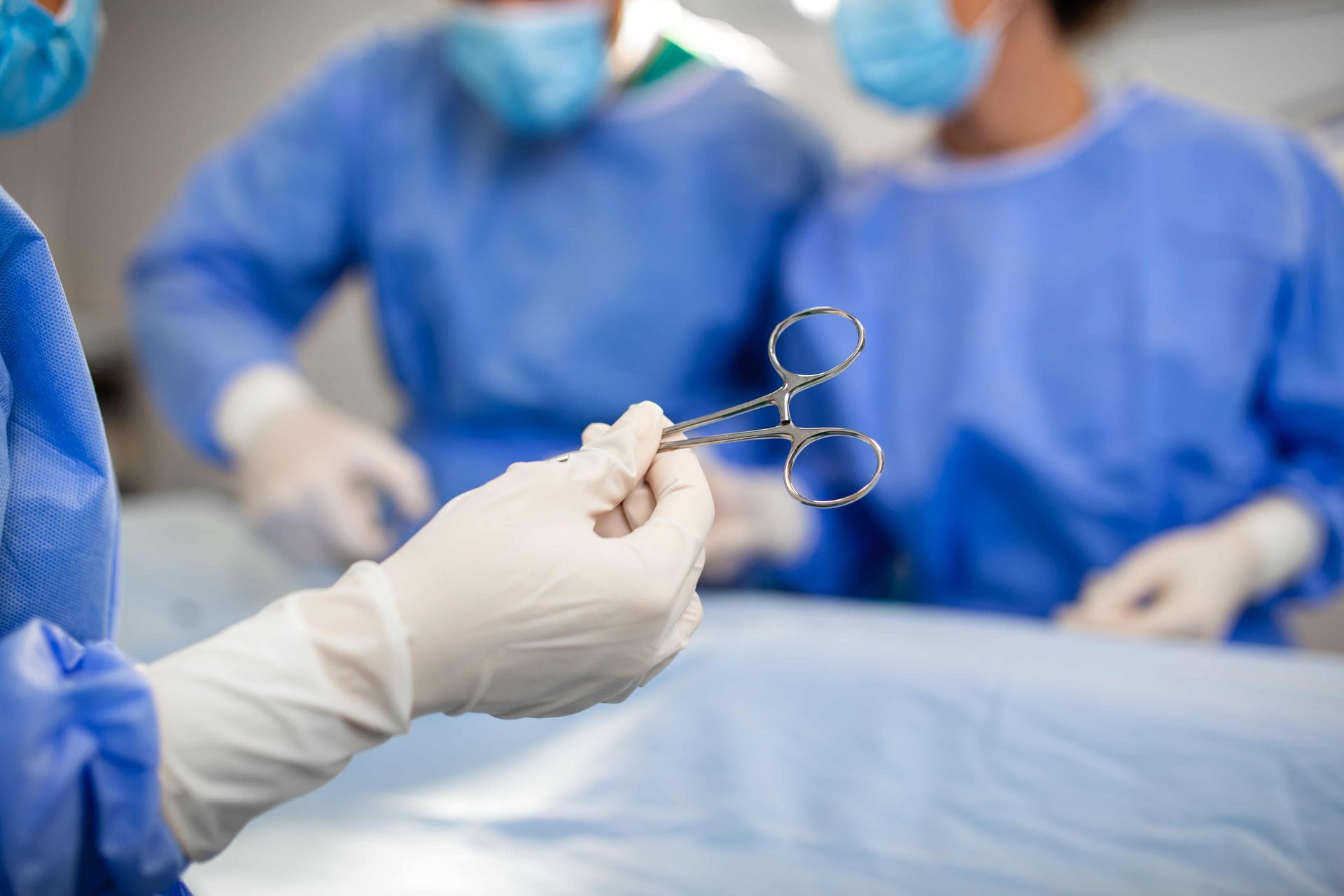 Médicos cirurgiões utilizam tesoura e materiais hospitalares durante cirurgia da válvula pela virilh