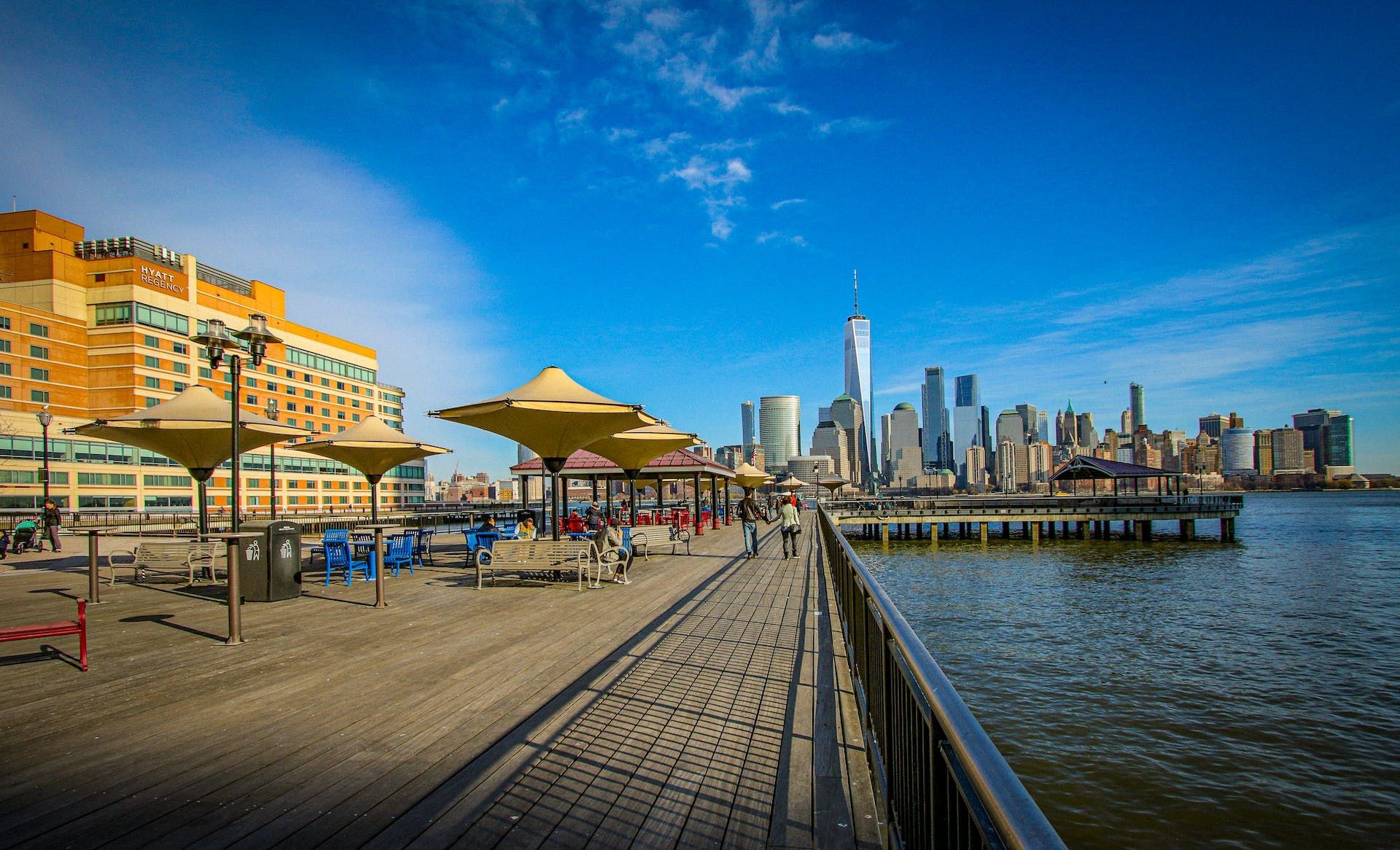 A pier with umbrellas and a city skyline in the background.