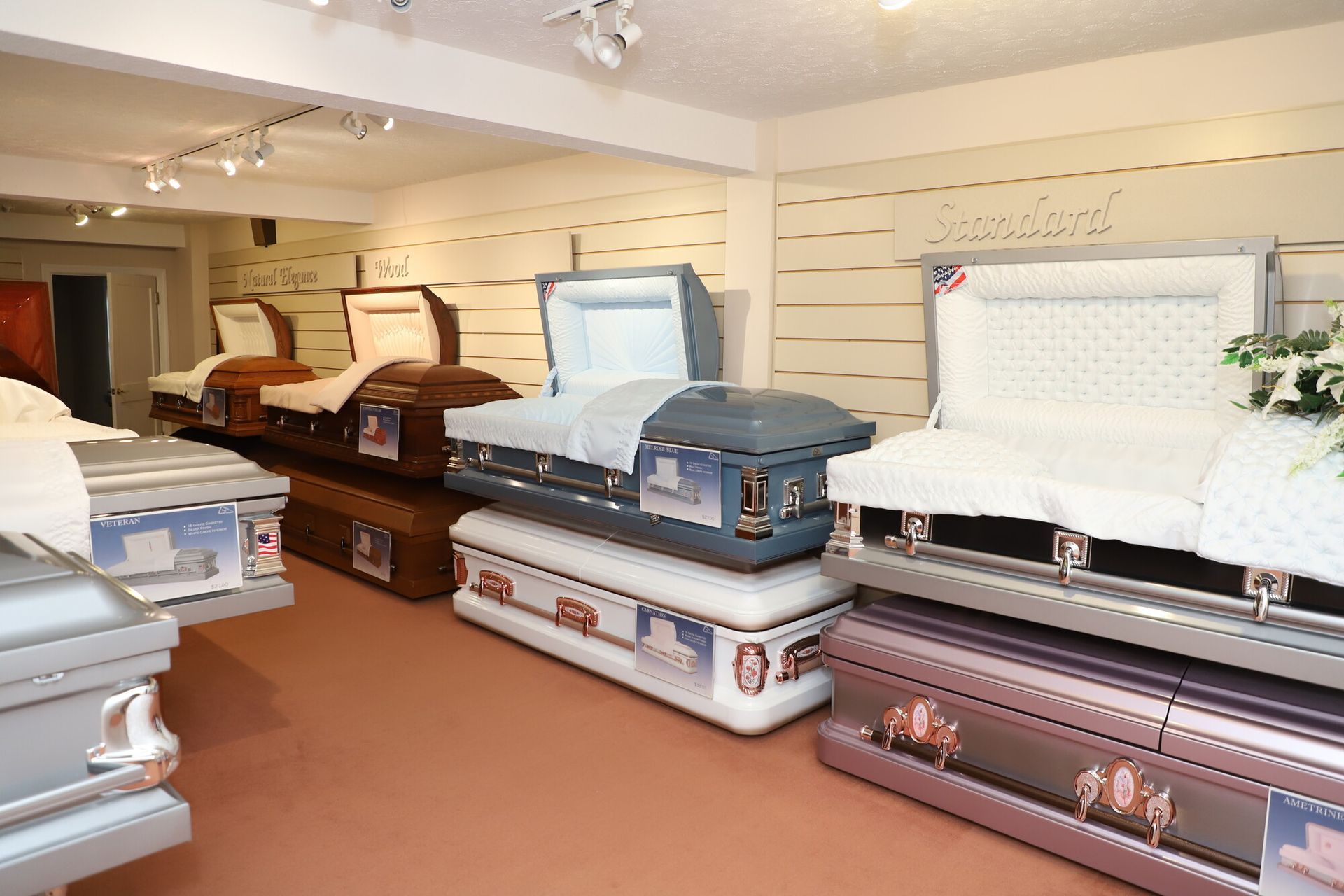Display room with several coffins arranged on shelves and platforms in a funeral showroom