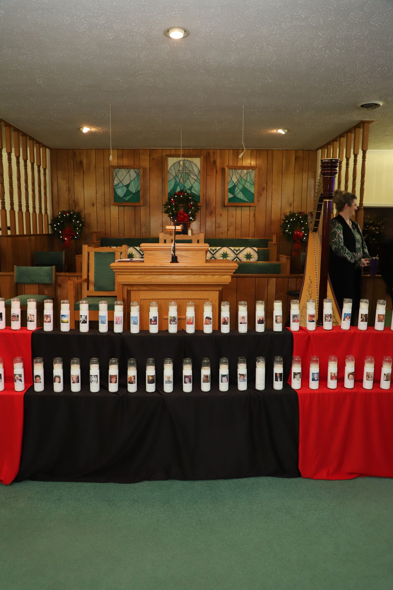 Memorial display with rows of small white bottles and red-black draping in a chapel-like room