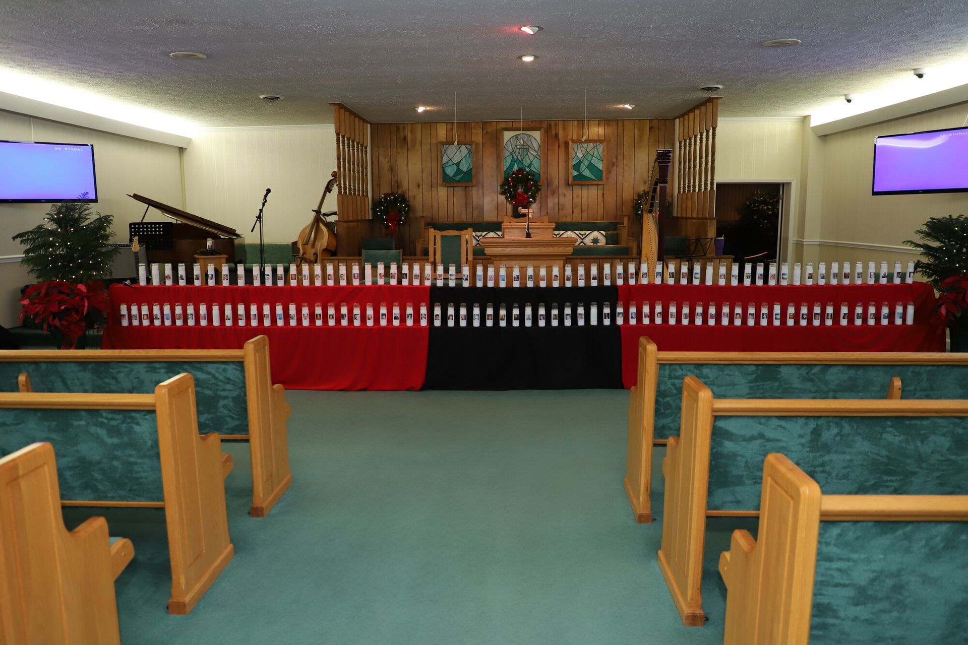 Church sanctuary with red-draped altar, pews, and screens at the front