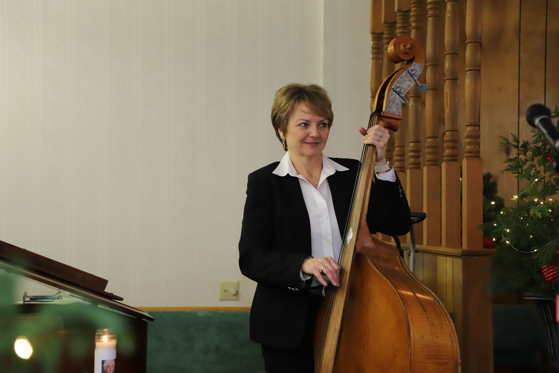 Woman in a black blazer stands beside an upright bass in a church-like interior