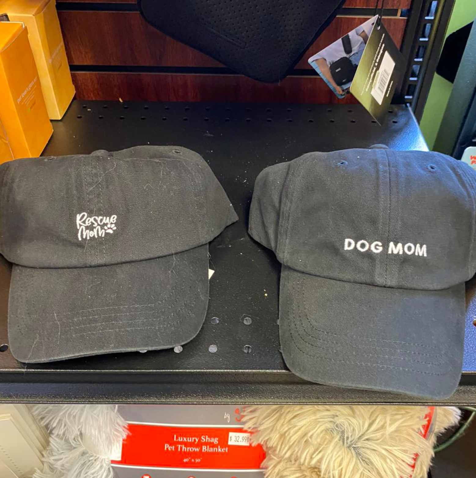 Two black hats that say dog mom are on a shelf