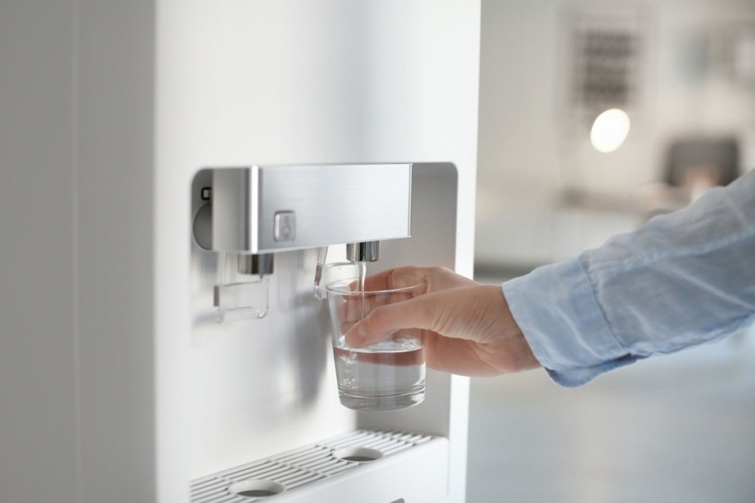 A person is pouring water into a glass from a water dispenser.