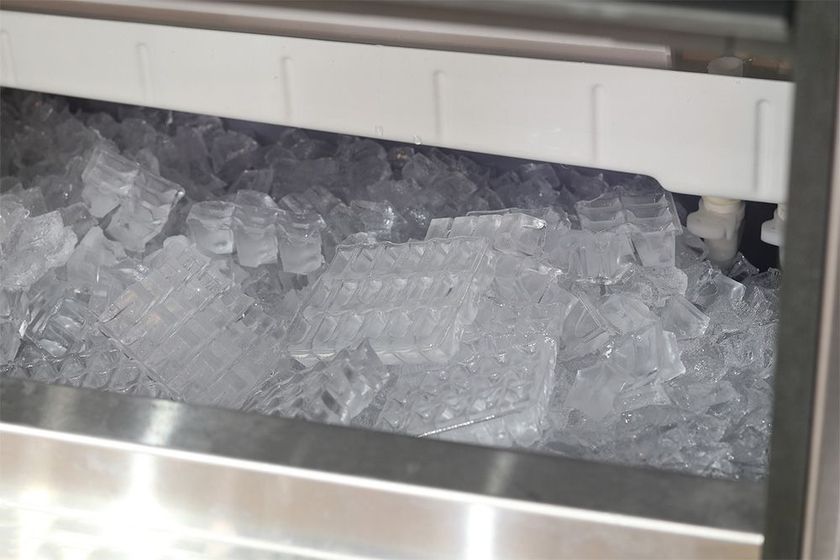 A stainless steel ice maker is filled with ice cubes.