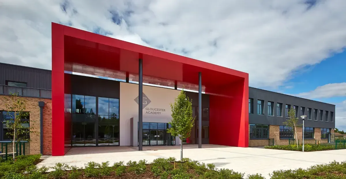 Modern office building with a bright red entrance canopy and landscaped front walkway