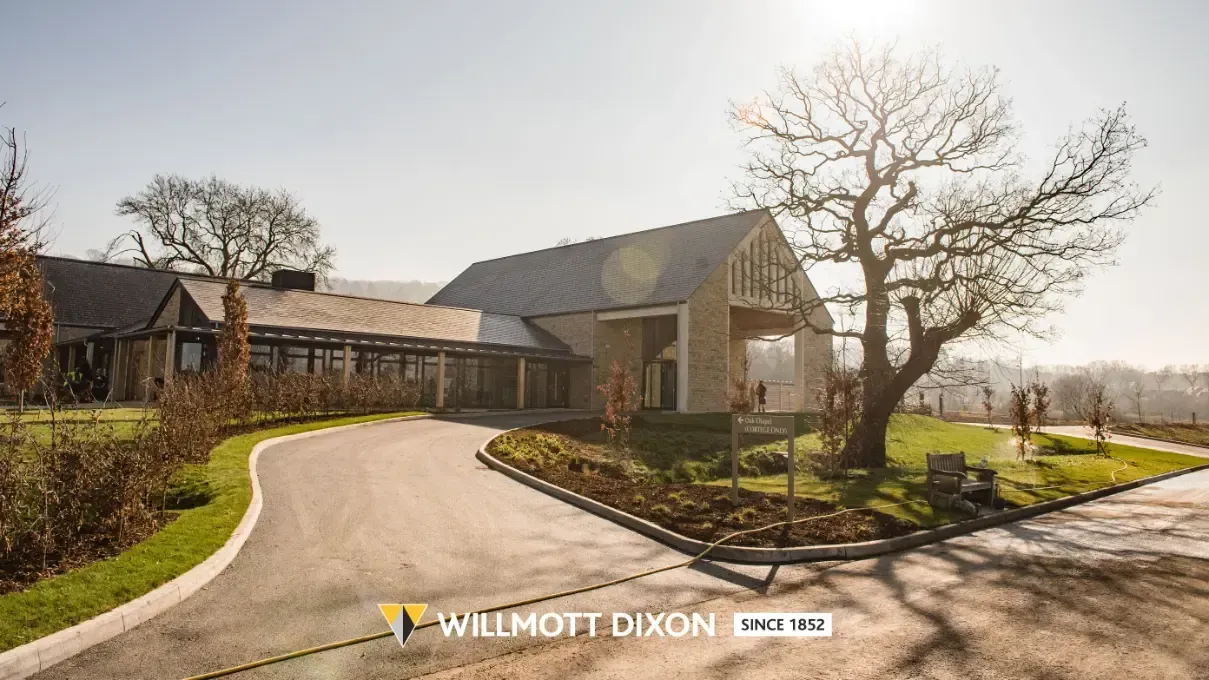 Country house with curved driveway, leafless trees, and landscaped front yard in warm sunlight