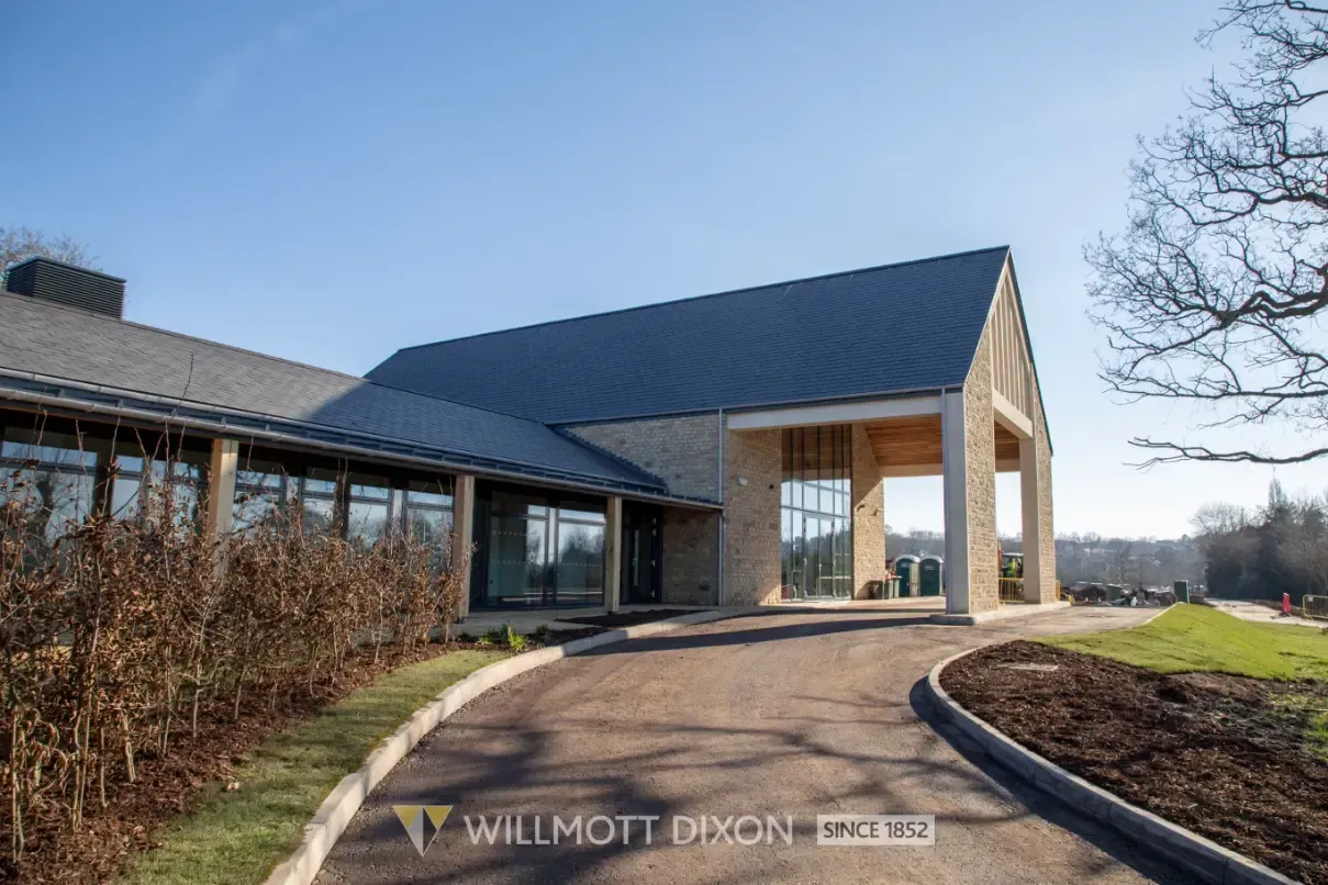 Modern house exterior with dark roof, wood accents, and a curved driveway under a blue sky