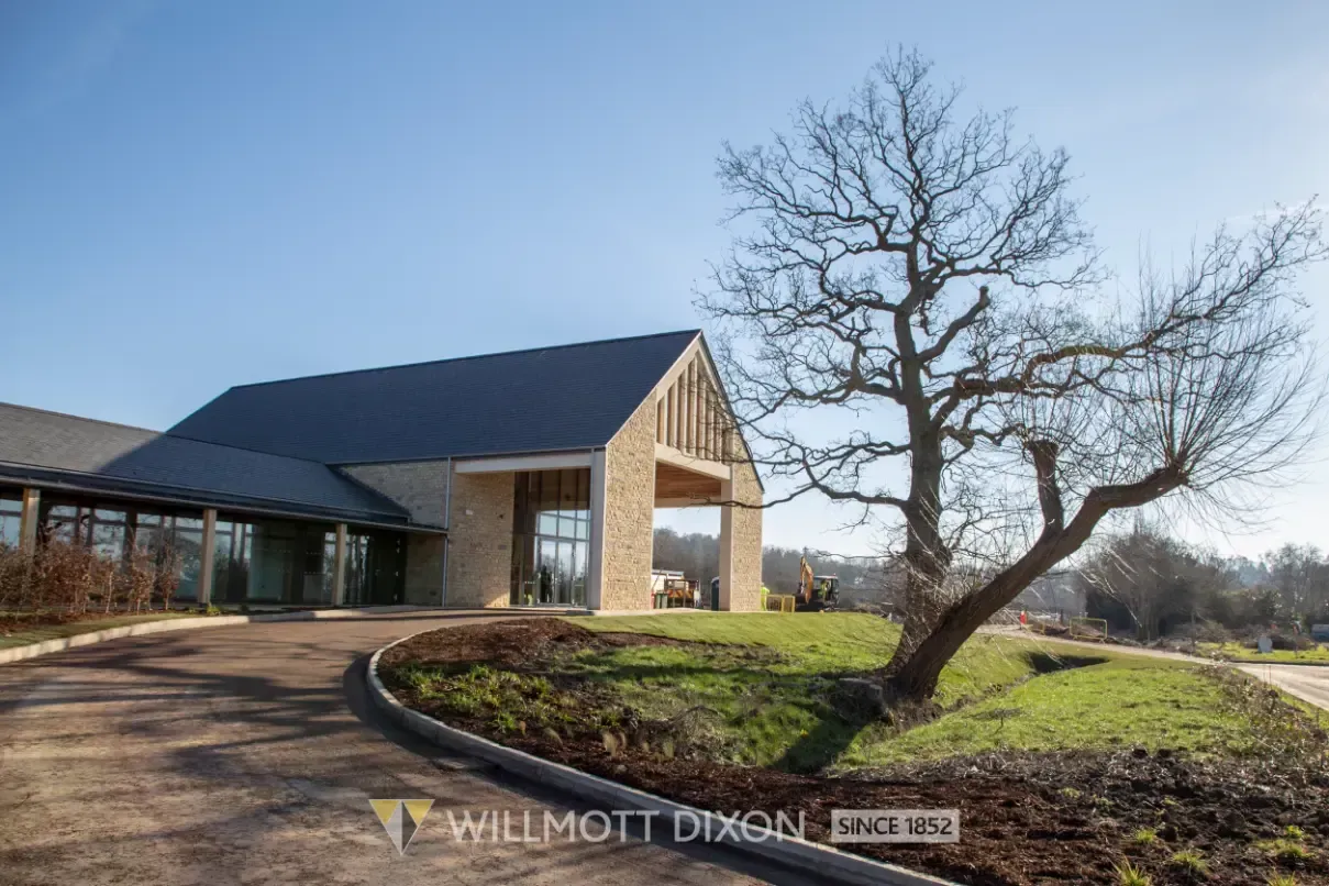 Modern building with a curved driveway and leafless tree on a sunny day