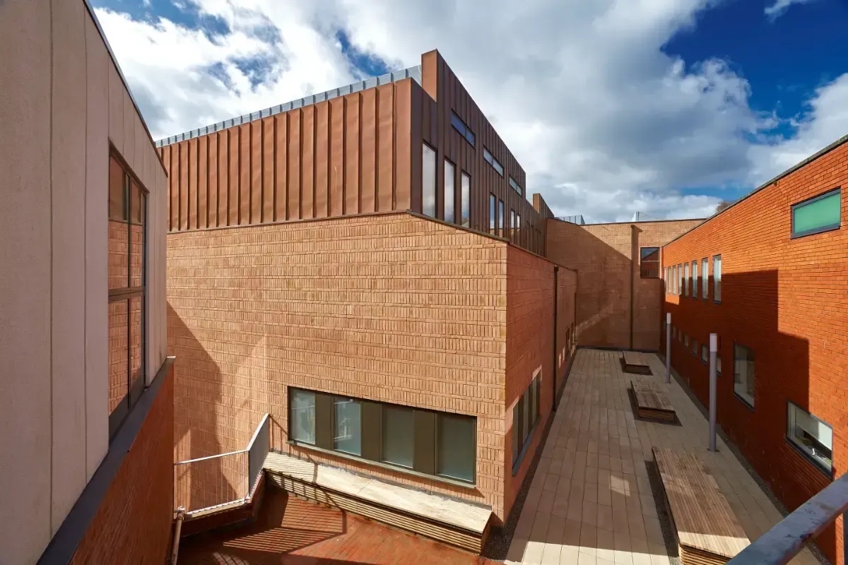 Modern brick buildings with a narrow courtyard and blue sky overhead