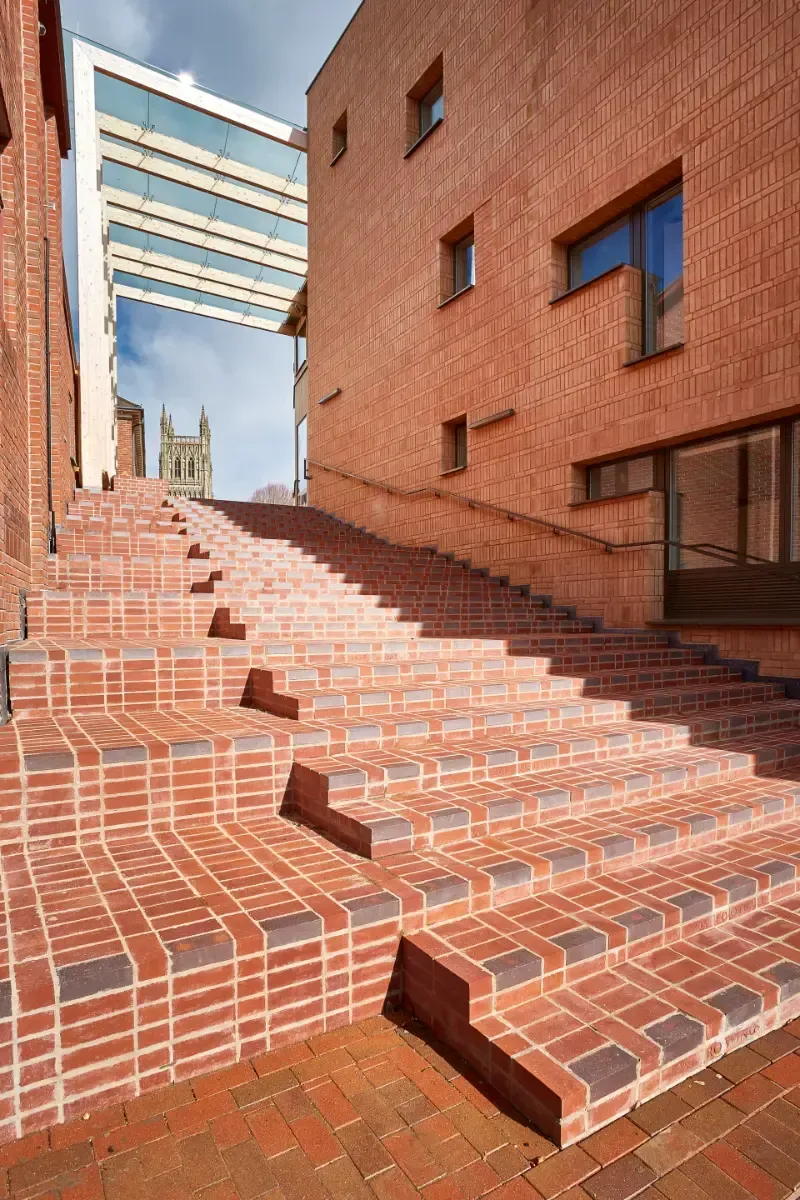 Brick staircase between red-brick buildings under a bright sky