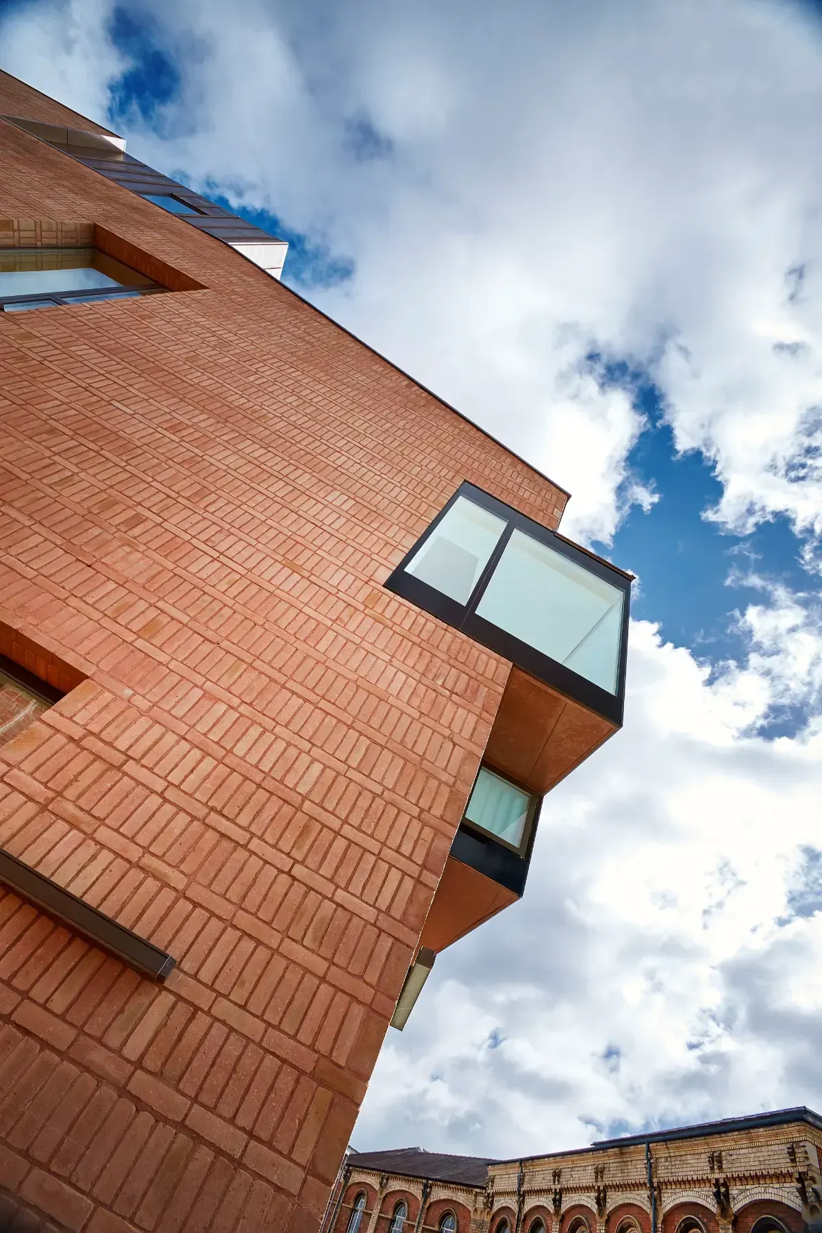 Brick building with angular windows against a cloudy blue sky