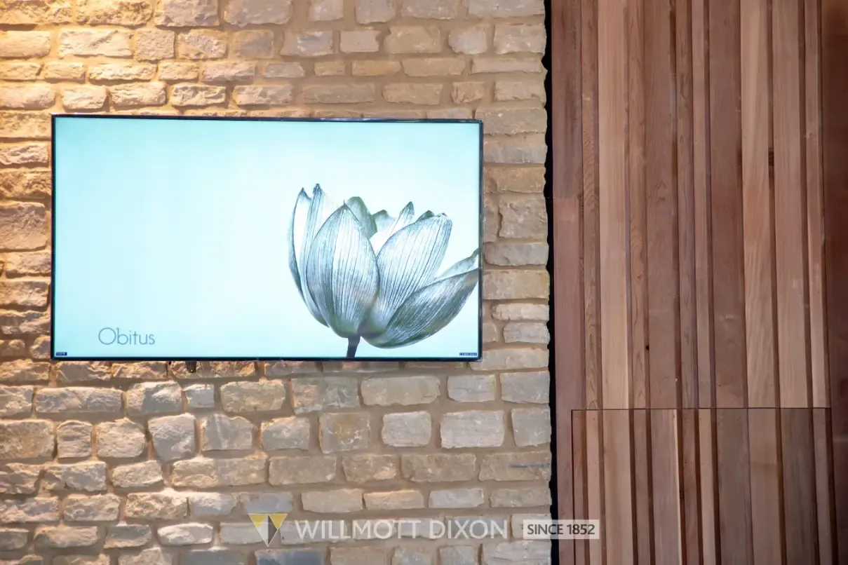 Framed floral artwork with a pale blue background on a stone and wood wall.