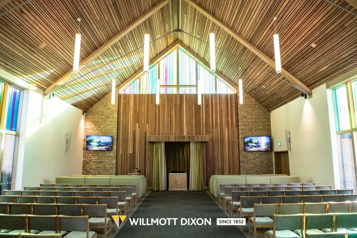 Church sanctuary with wooden vaulted ceiling, pews, altar, and hanging lights