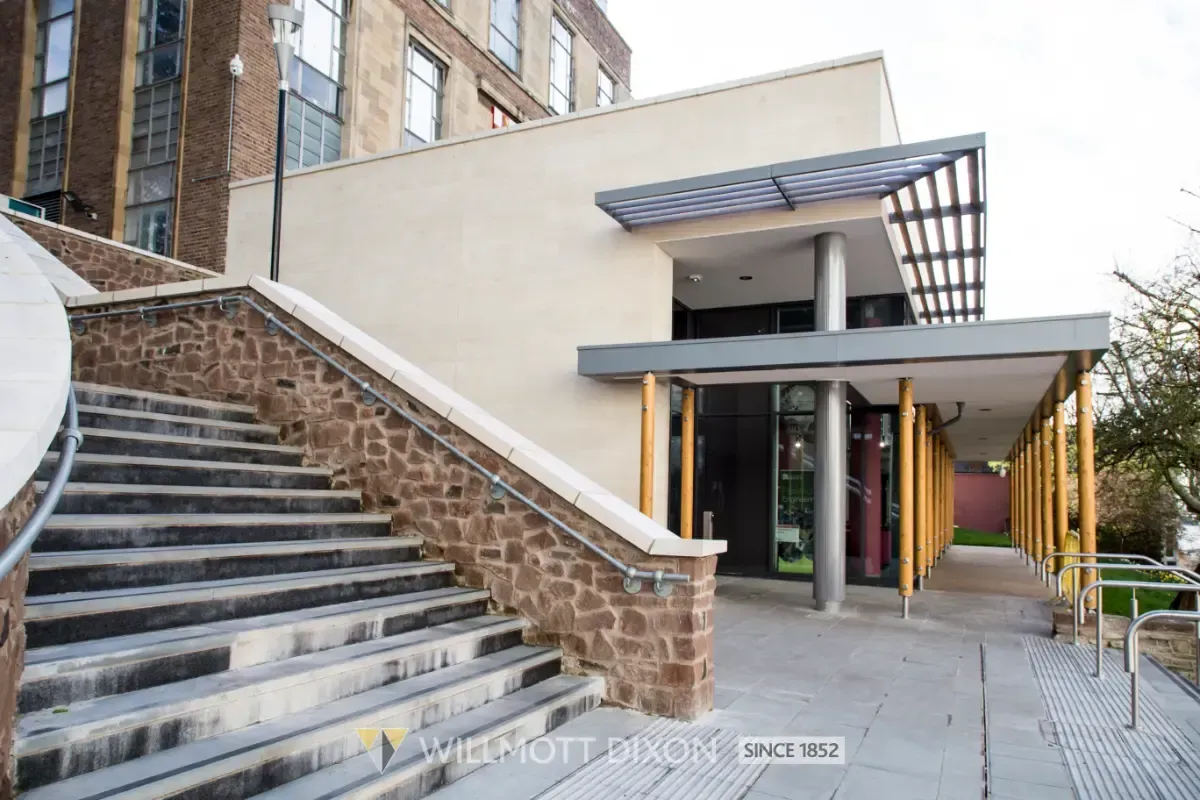 Building entrance with stairs on the left and an accessible covered walkway on the right