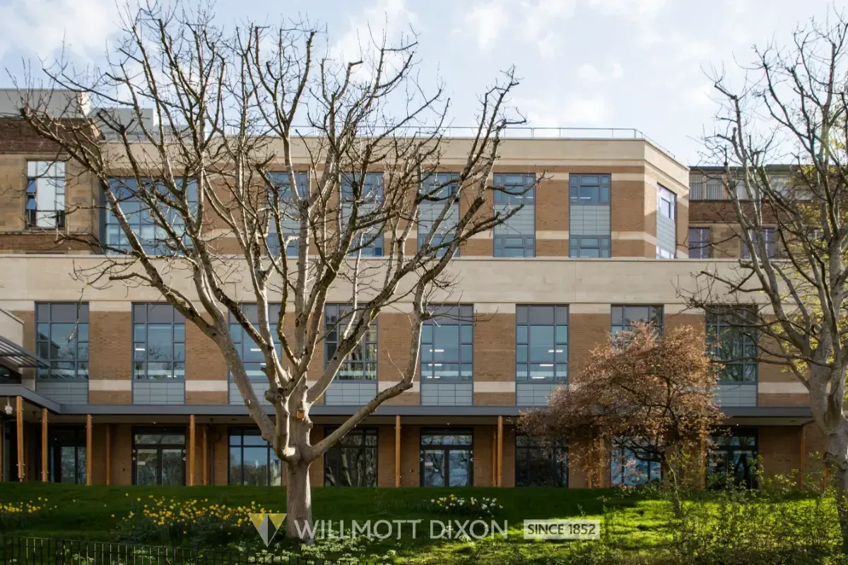 Modern brick school building with bare trees and a sign reading “Waddell Dickson” in front